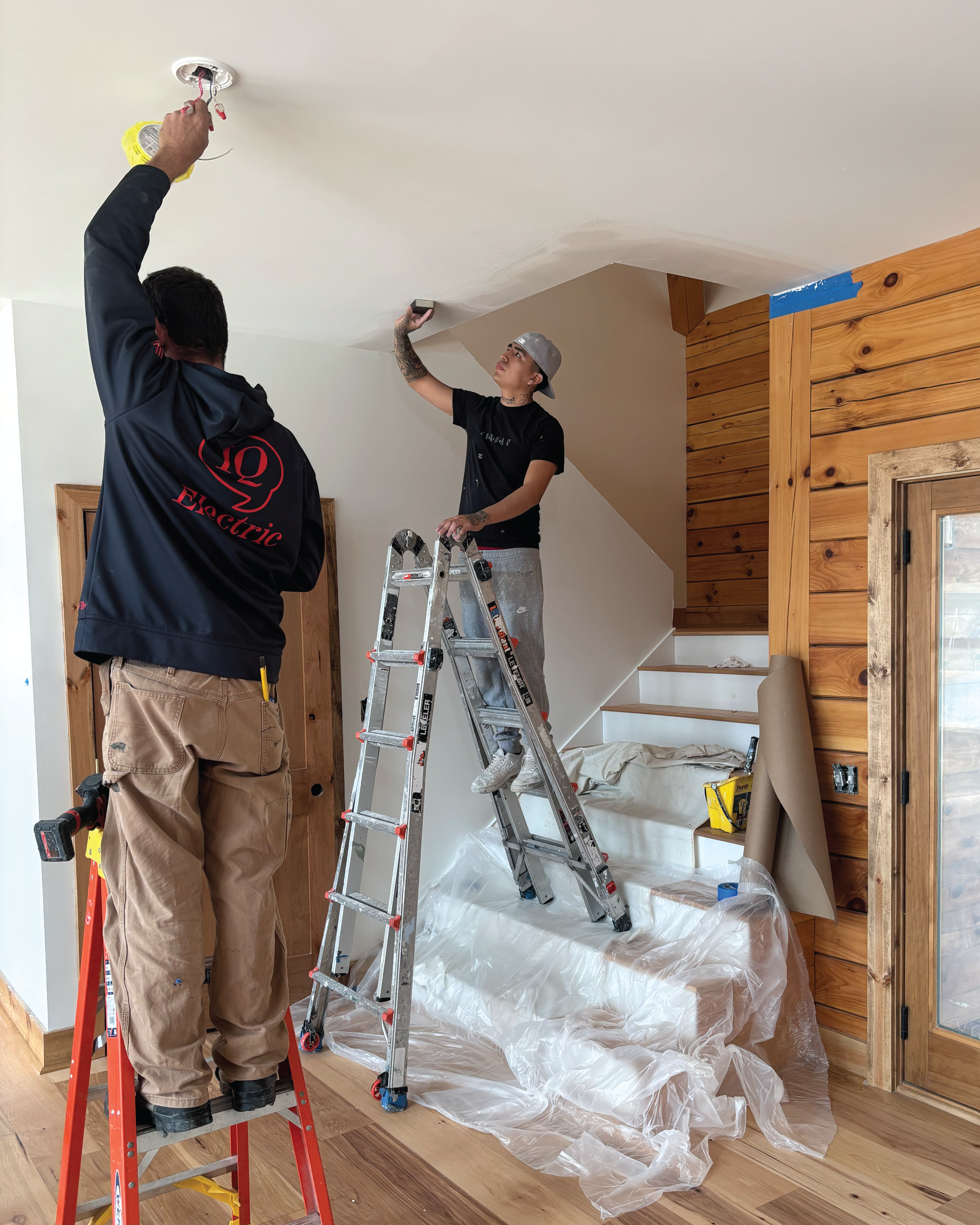 Residential home's interior full repaint and crew members installing lighting and sanding ceiling