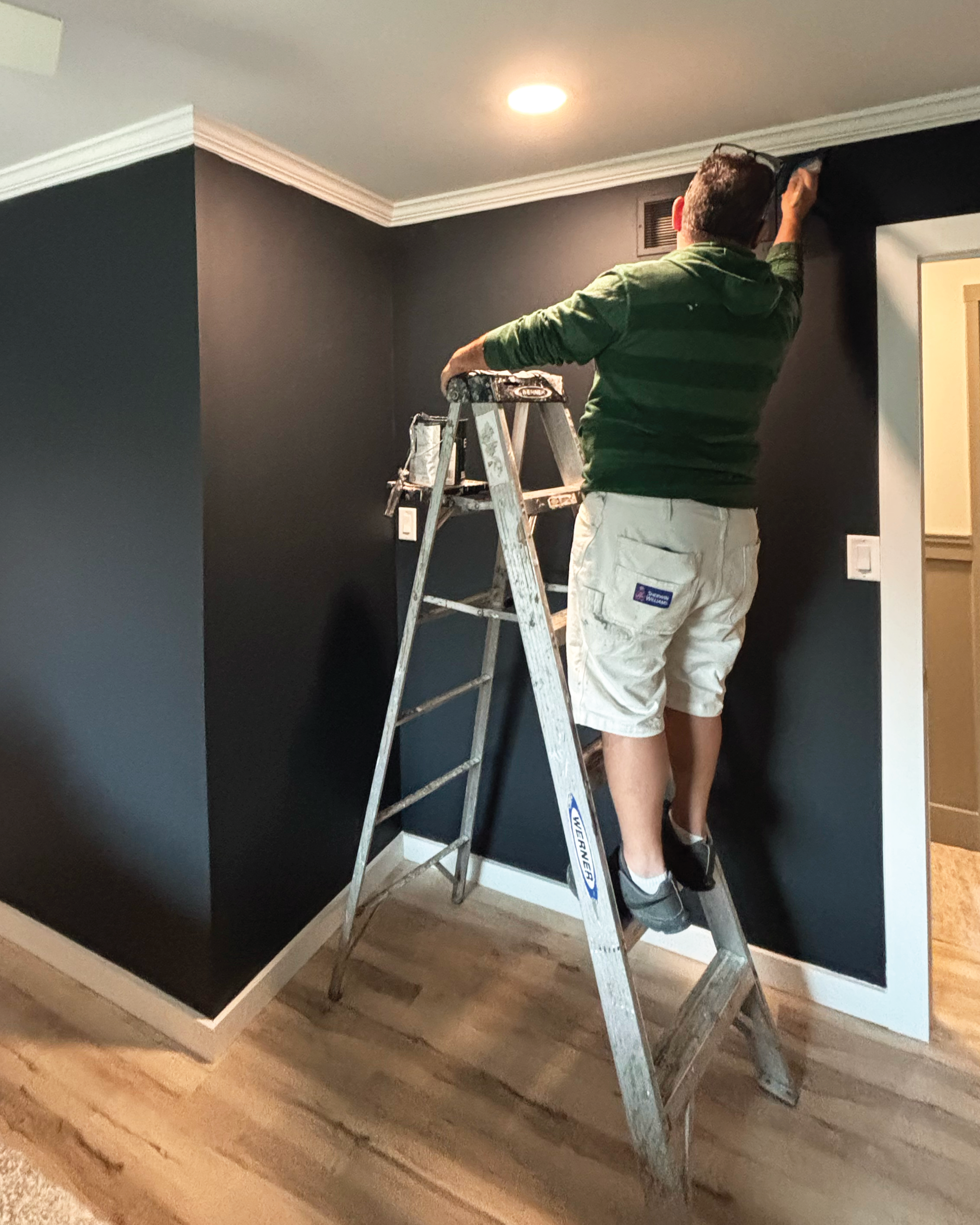 Residential home's interior full repaint and crew member on ladder painting bedroom wall