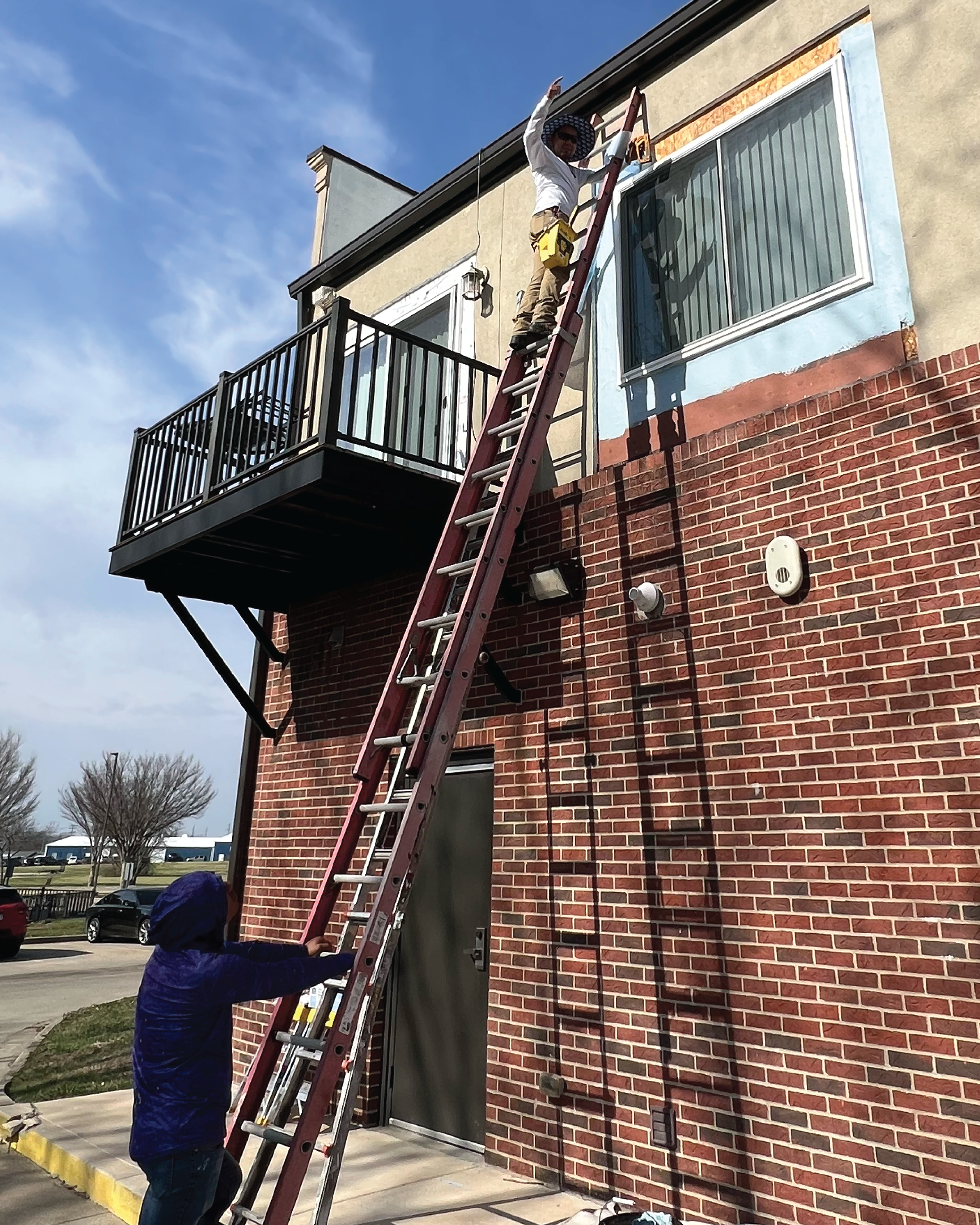 Crew working on a apartment's exterior, repairing, and repainting
