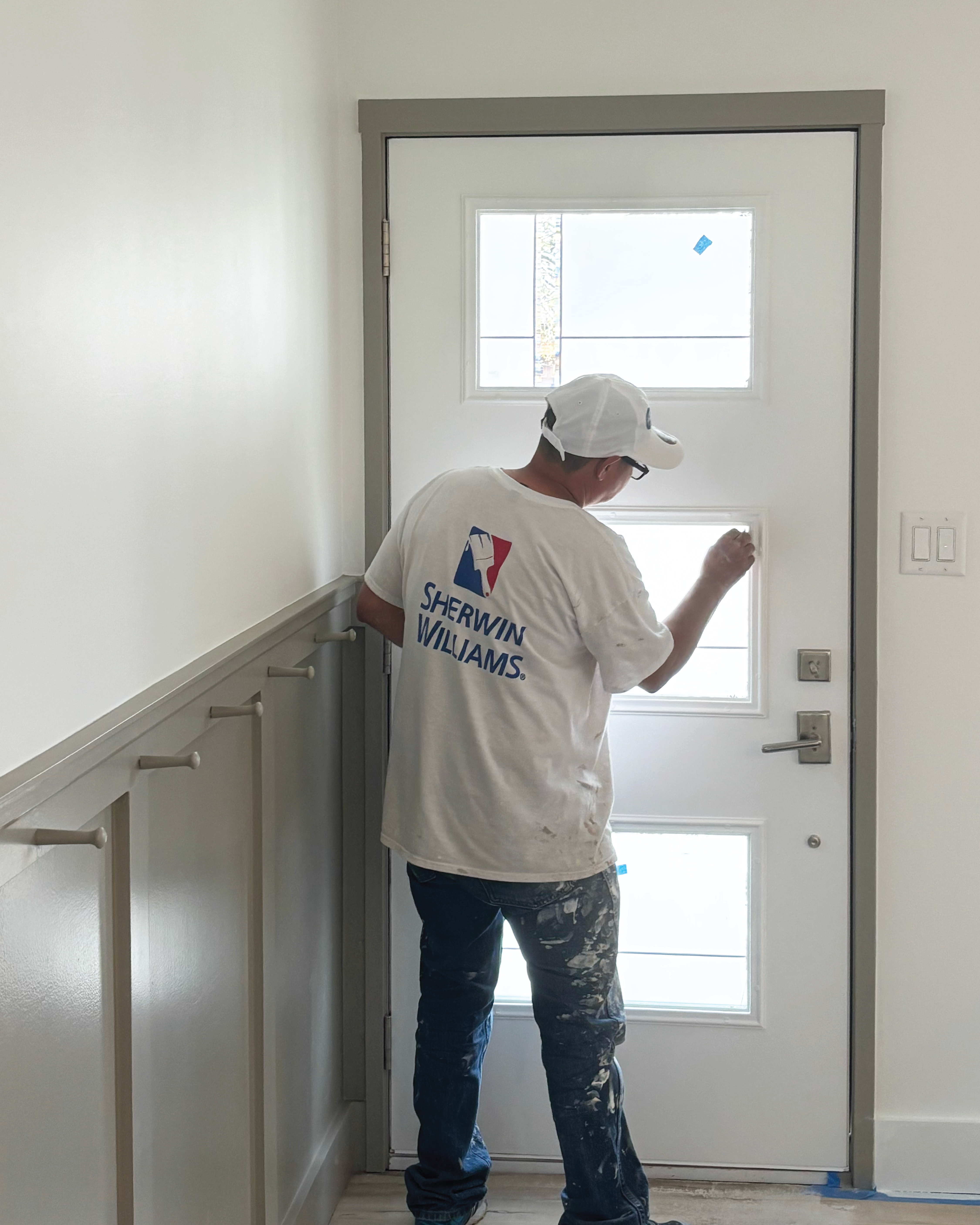 Residential home front door getting repainted and touched up by a crew member.