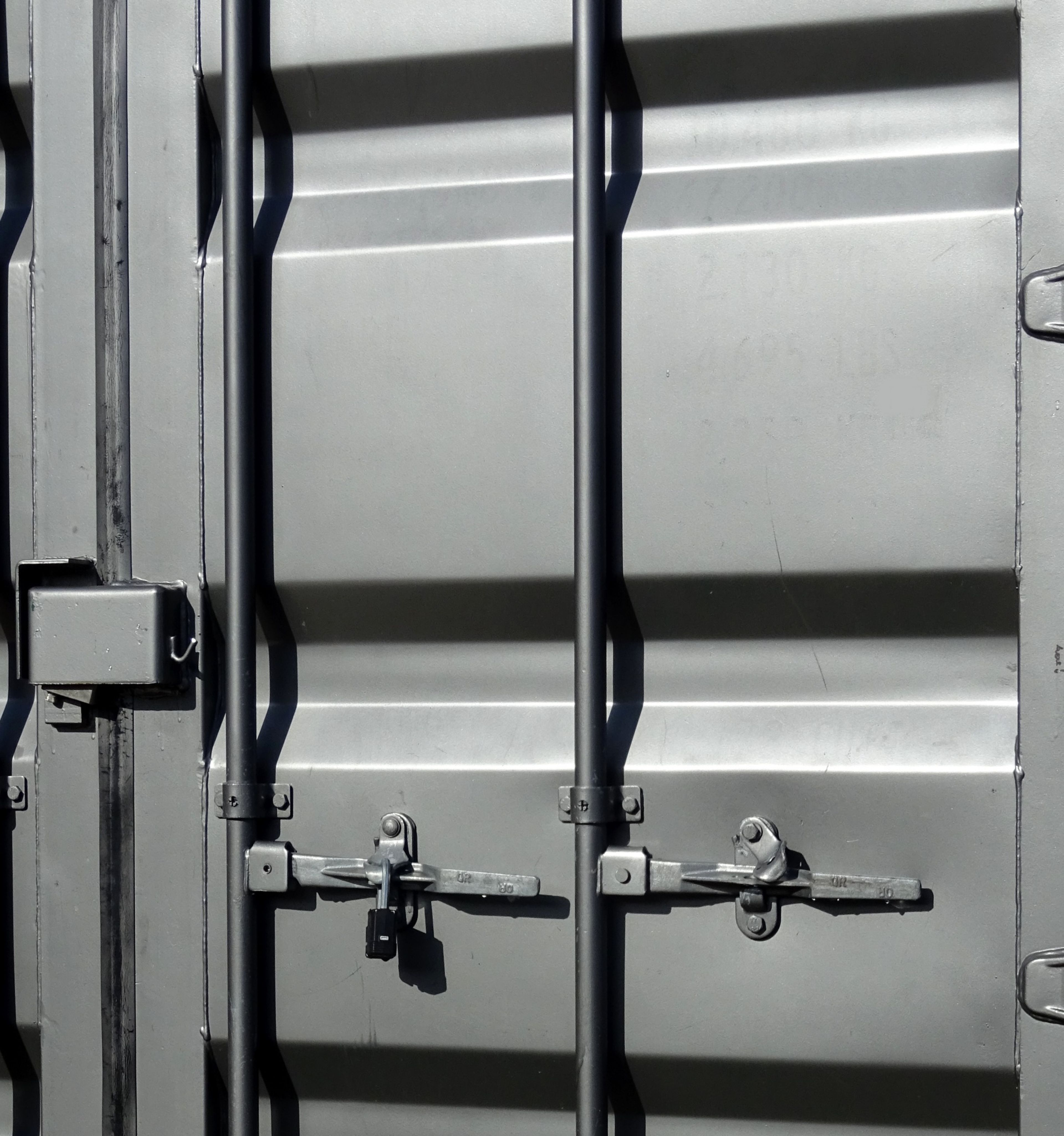 Gray shipping container end doors with vertical locking bars, handles, and a padlock