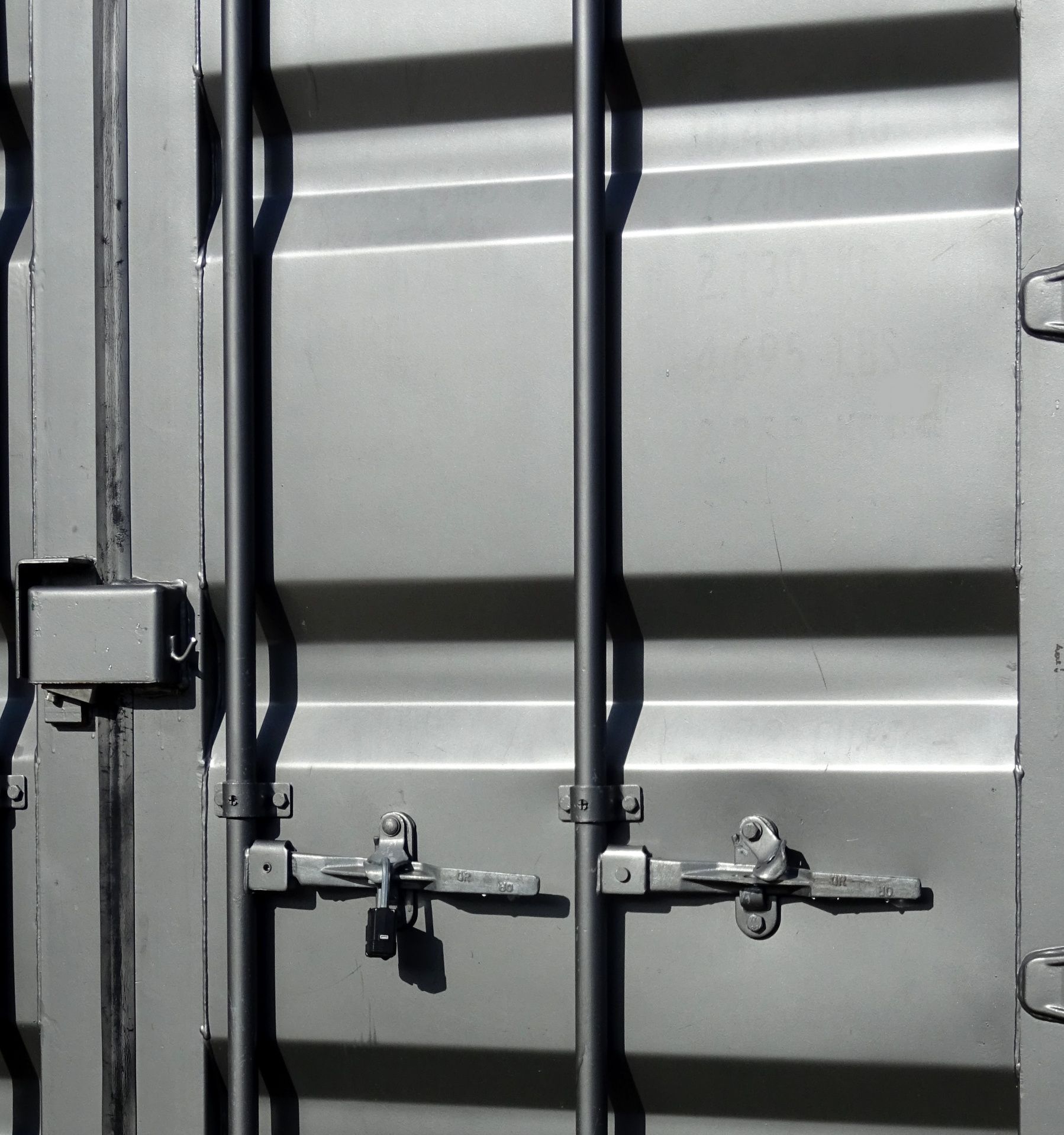 Gray shipping container end doors with vertical locking bars, handles, and a padlock