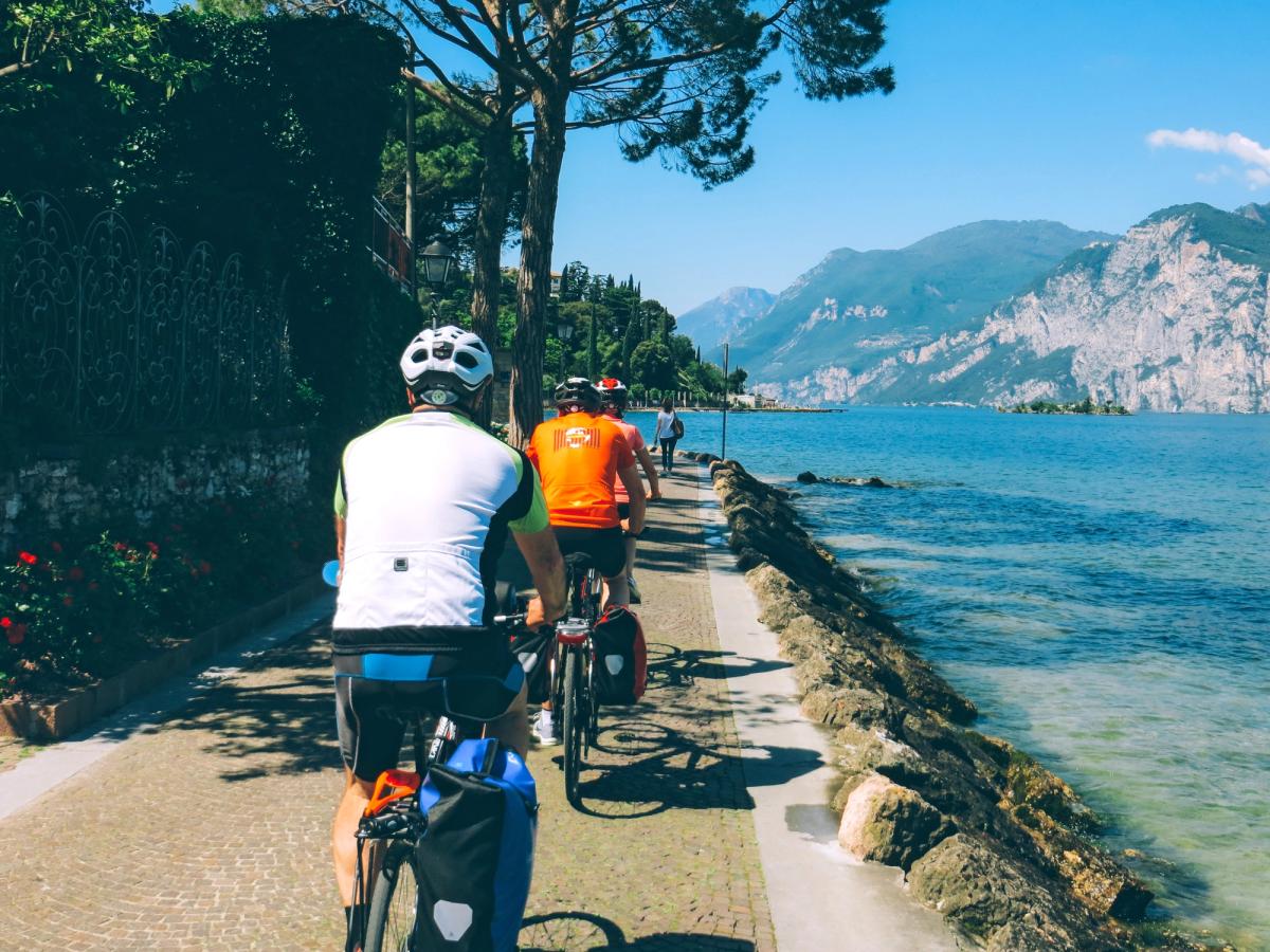 cyclists on a path alongside Lake Garda in Italy, likely on the Limone sul Garda Bike Path
