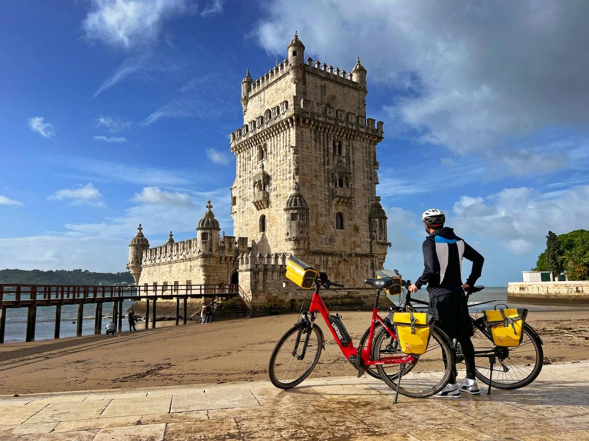 the iconic Belém Tower (Torre de Belém) in Lisbon, Portugal, with a person and bicycles in the foreground