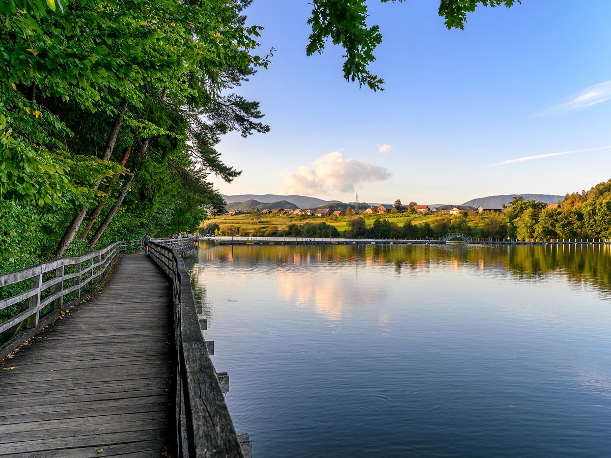 a wooden walkway along the shore of Šmartinsko Lake, also known as Šmartinsko Jezero, in Slovenia