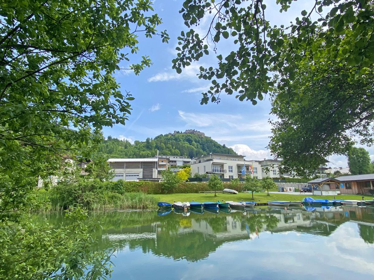 a scenic view of a body of water with buildings on the opposite shore, backed by a hill or mountain