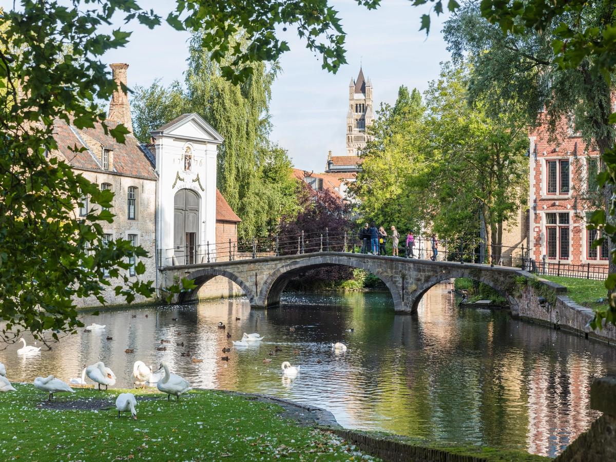 the Minnewater Bridge in Bruges, Belgium. The bridge crosses the "Lake of Love," or Minnewater, which is a key feature of Minnewater Park