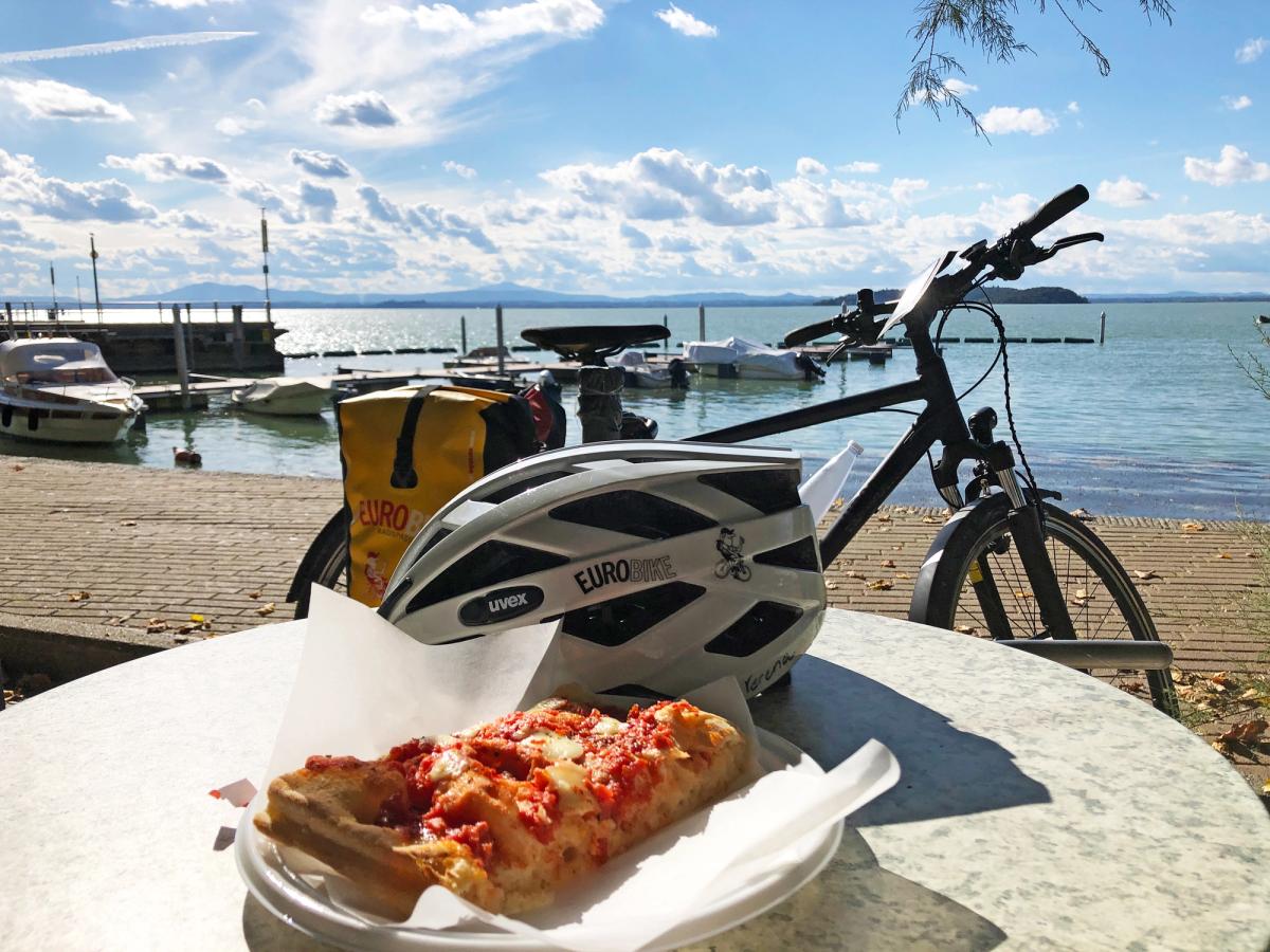 a scenic moment, likely during a cycling tour or a leisurely bike ride, with a focus on a break by a body of water, possibly Lake Garda in Italy