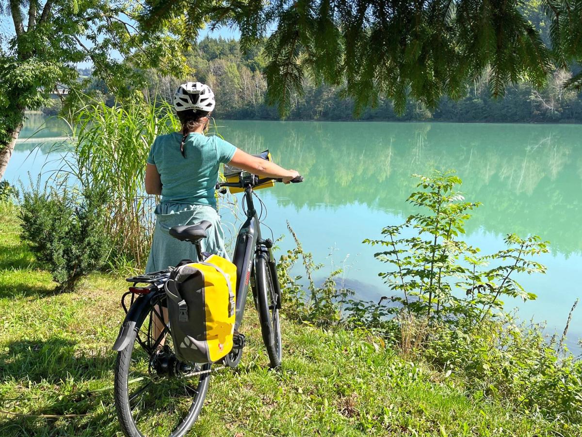 a moment of a person enjoying a cycling holiday near a body of water, likely a lake or river, in a scenic, natural setting