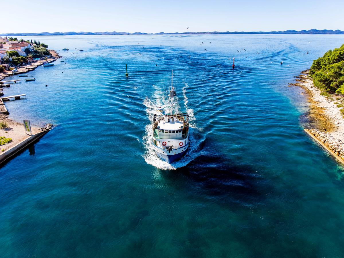 boat navigating a narrow channel of a scenic coastal area or a national park with islands and a Dalmatian Coast landscape