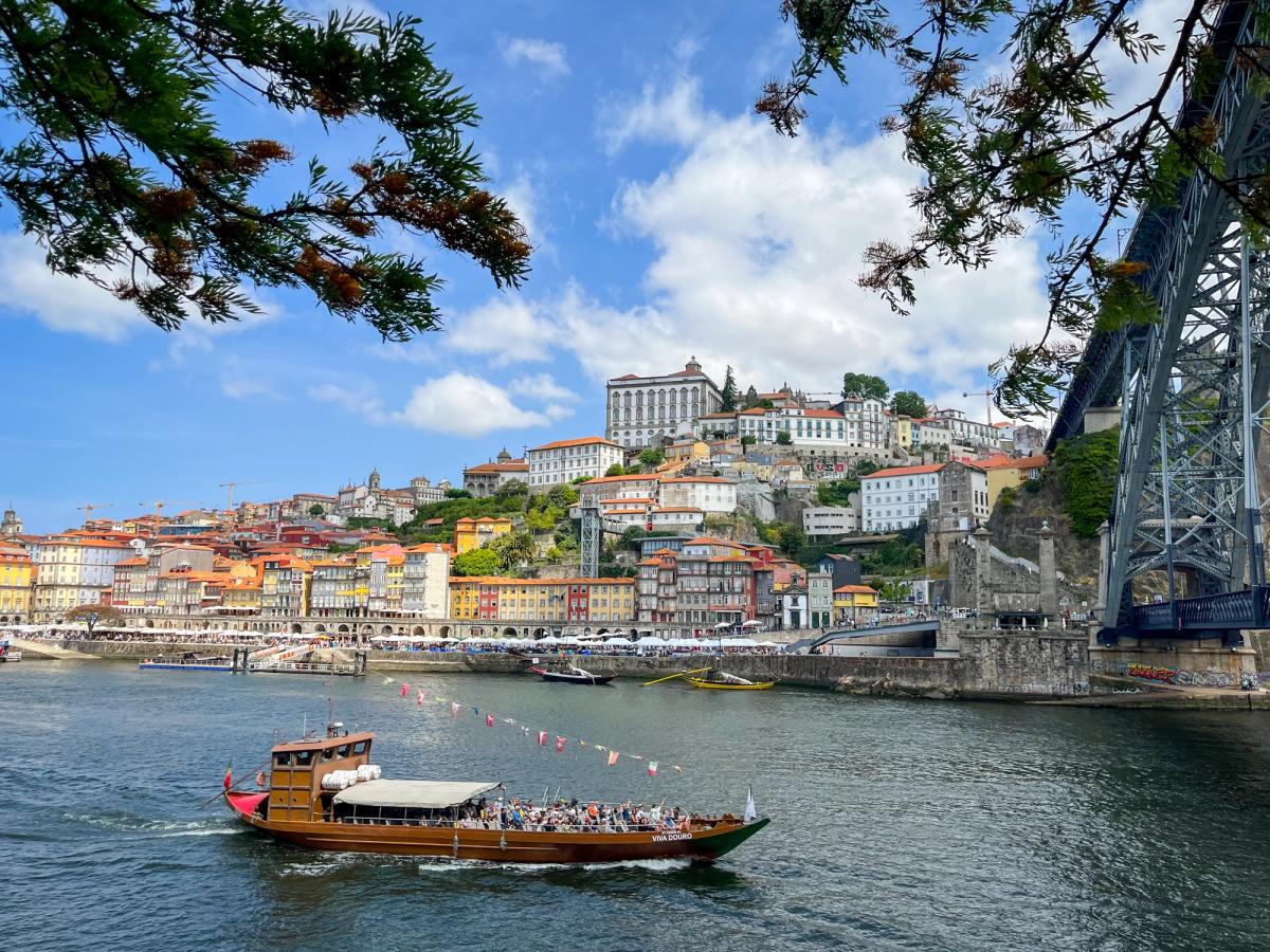 a scenic view of the Douro River in Porto, Portugal, featuring the iconic Dom Luís I Bridge and the colorful Ribeira district