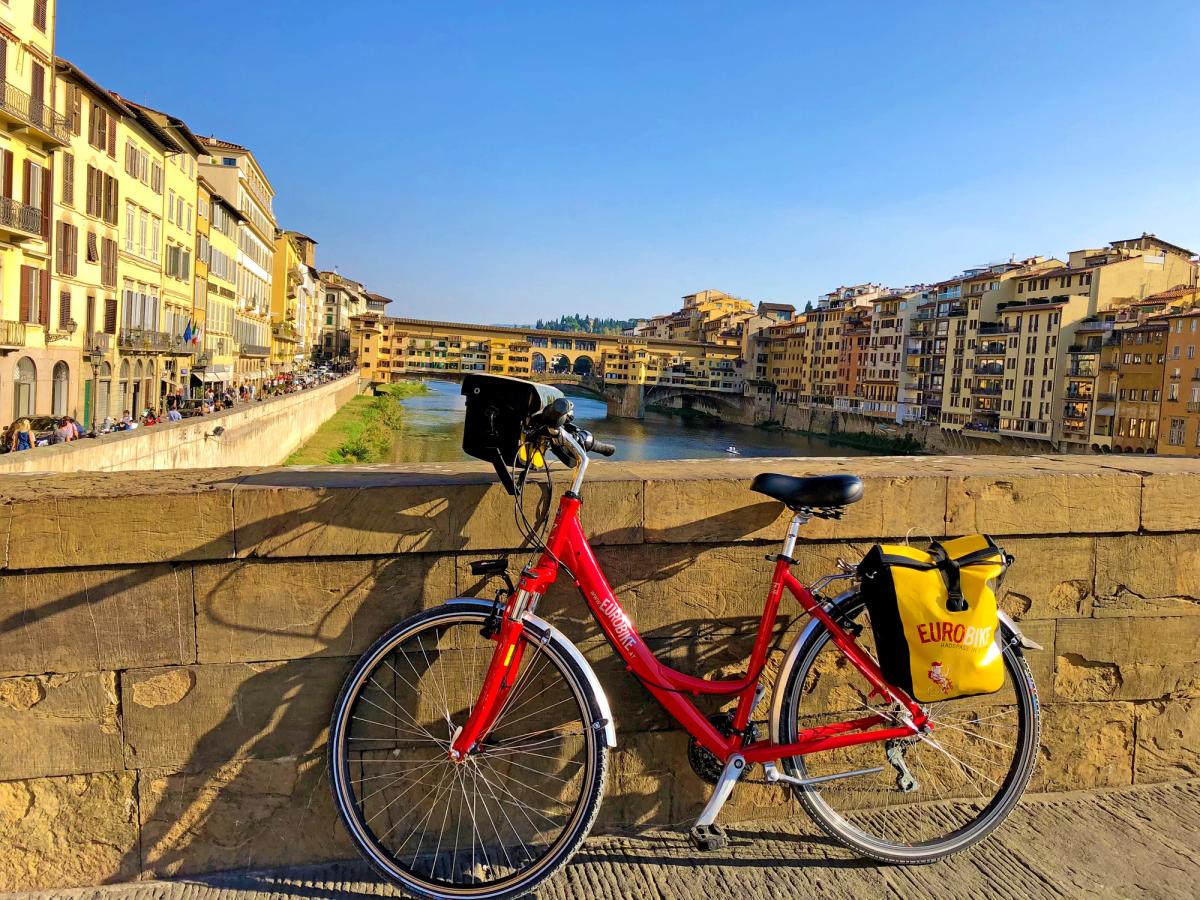 a red bicycle on the Ponte Vecchio in Florence, Italy, likely during a cycling tour