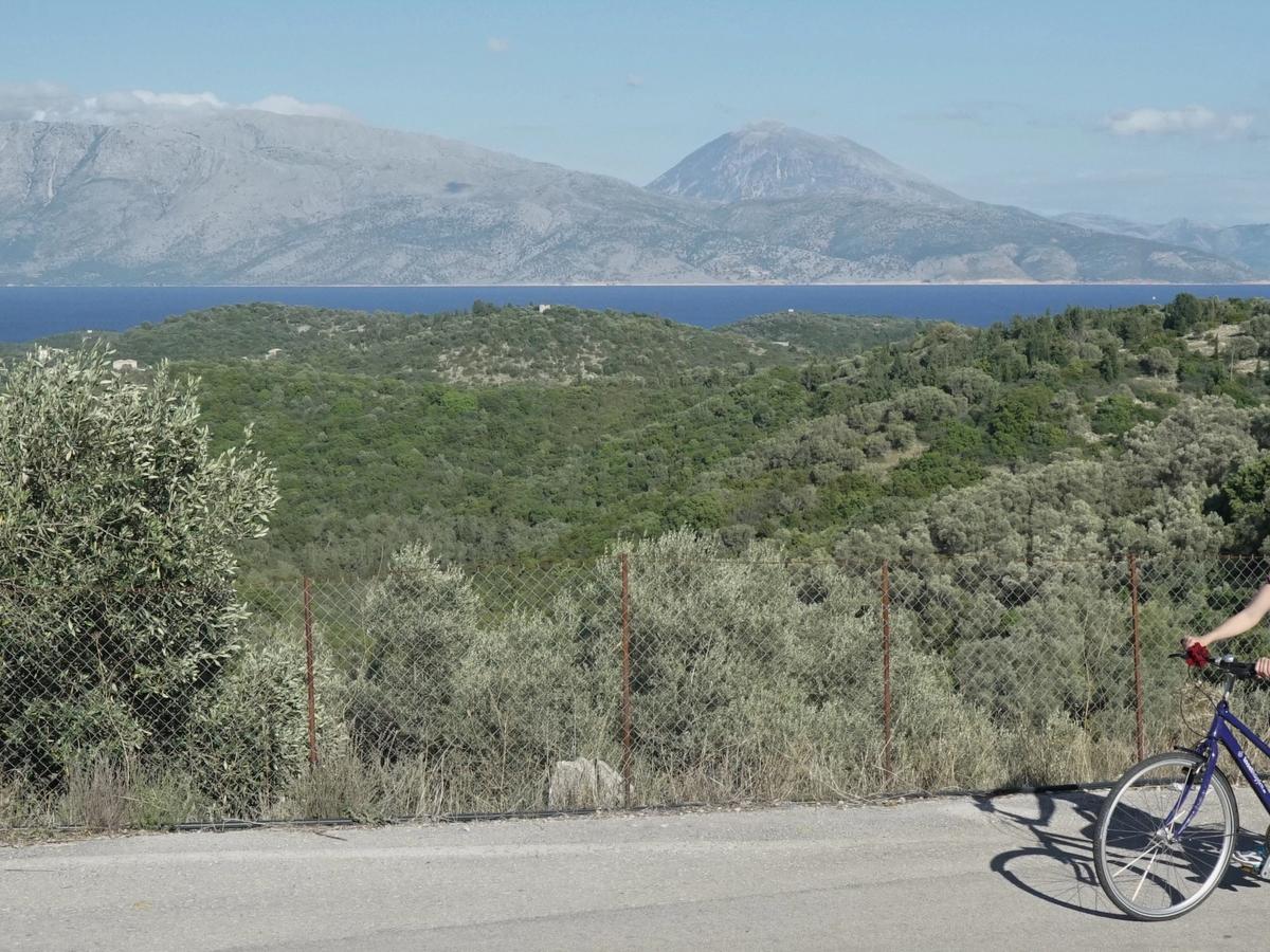cycling in a scenic, hilly, and potentially coastal area of Greece, likely on a cycling holiday or tour. 