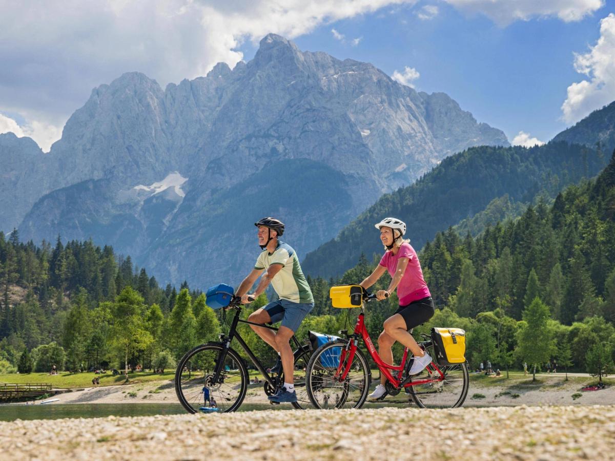 Two people cycling in Triglav National Park, Slovenia, with the Julian Alps in the background