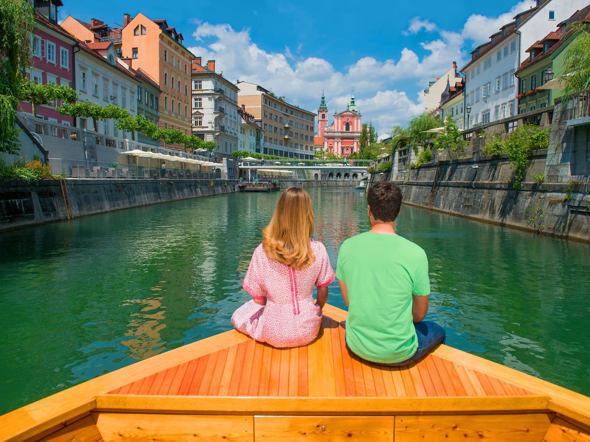 a couple on a boat on the Ljubljanica River in Ljubljana, the capital city of Slovenia. The river is a notable landmark of the city, flowing through its old city center