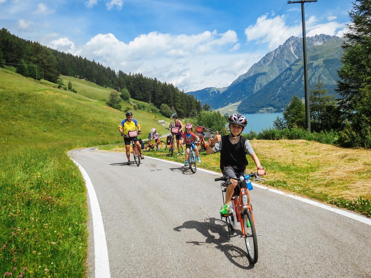 Family cycling along the river Adige