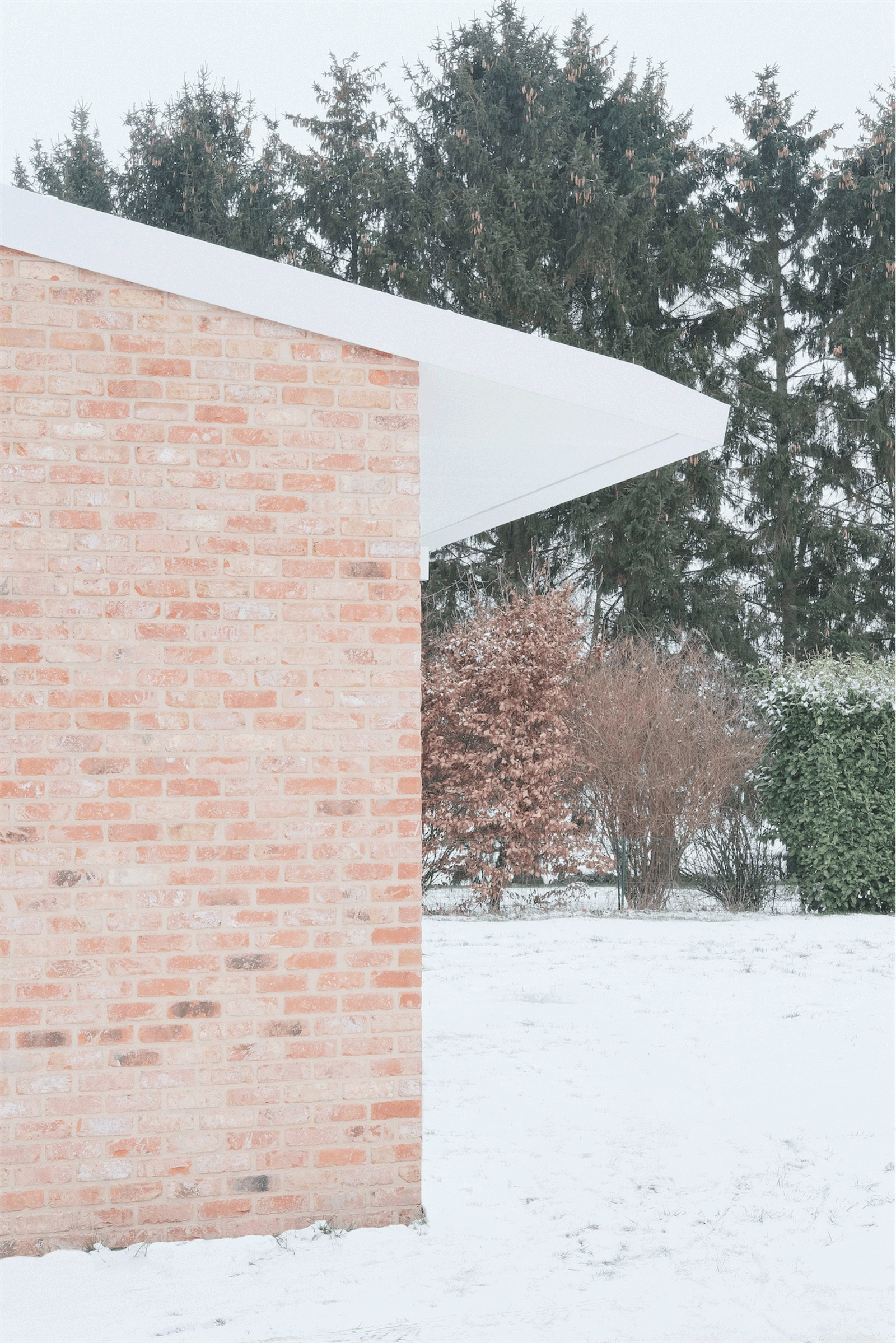 Snow-covered entrance canopy projecting from a brick wall