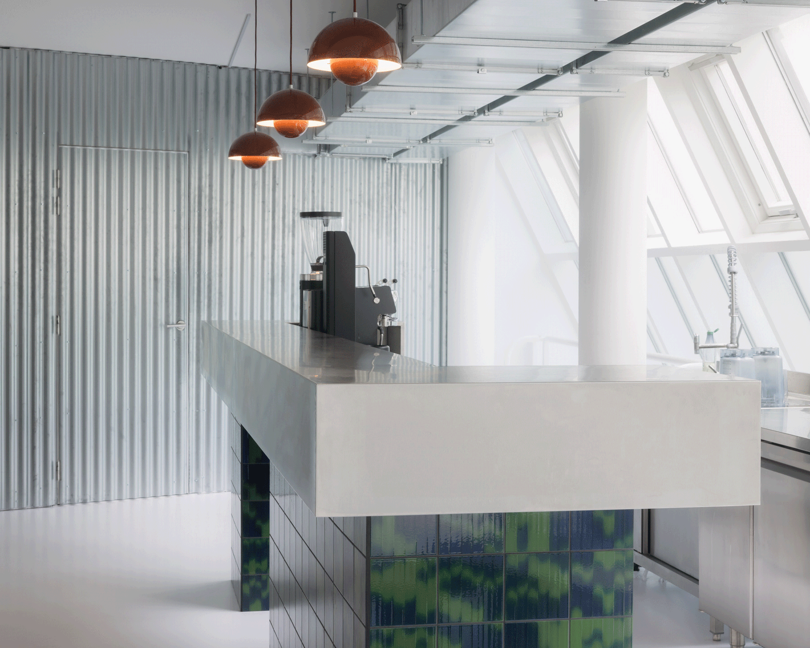 Angular white juice-bar counter beneath copper pendant lights