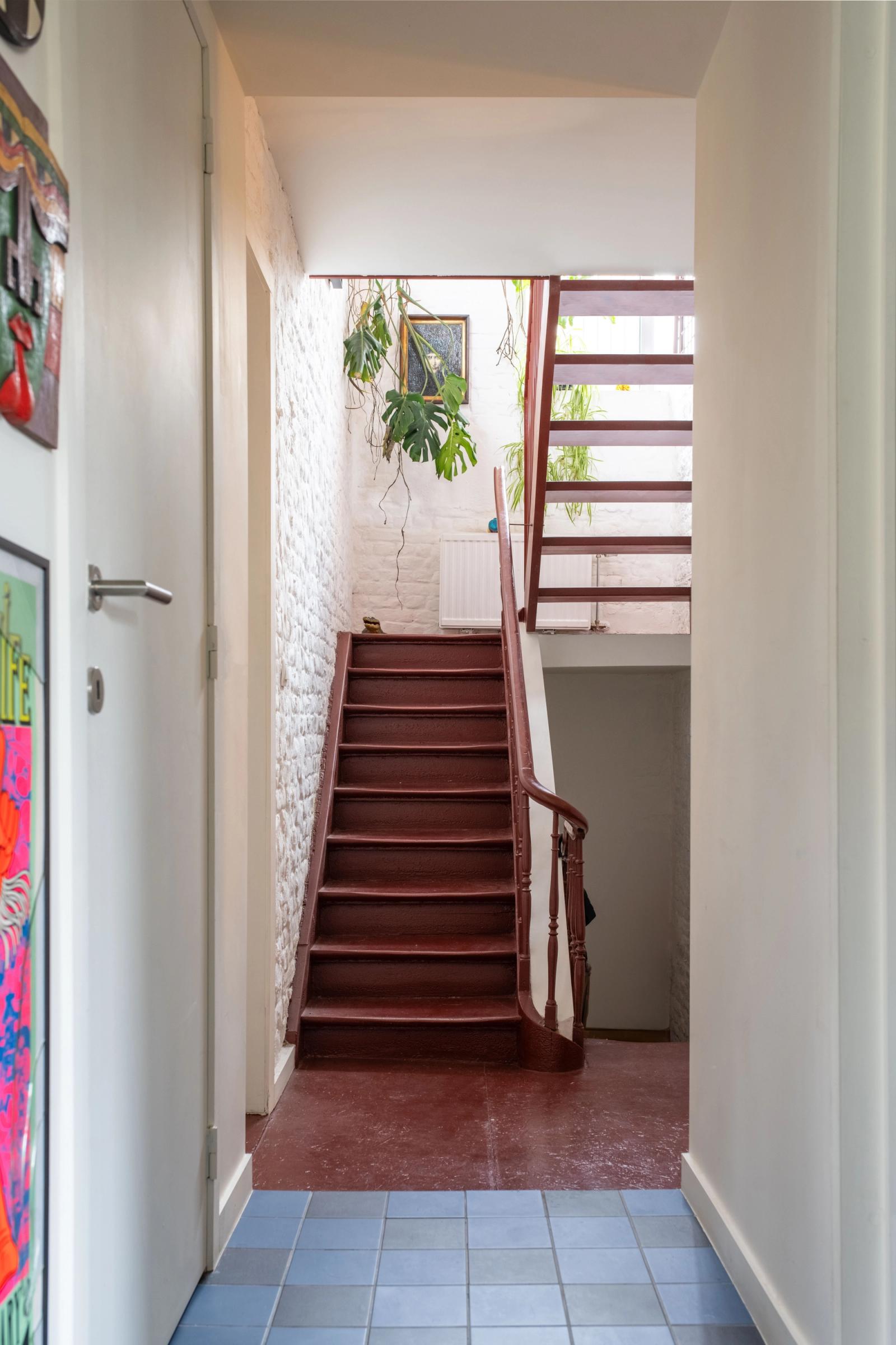 Narrow entrance passage with a red stair and translucent side wall