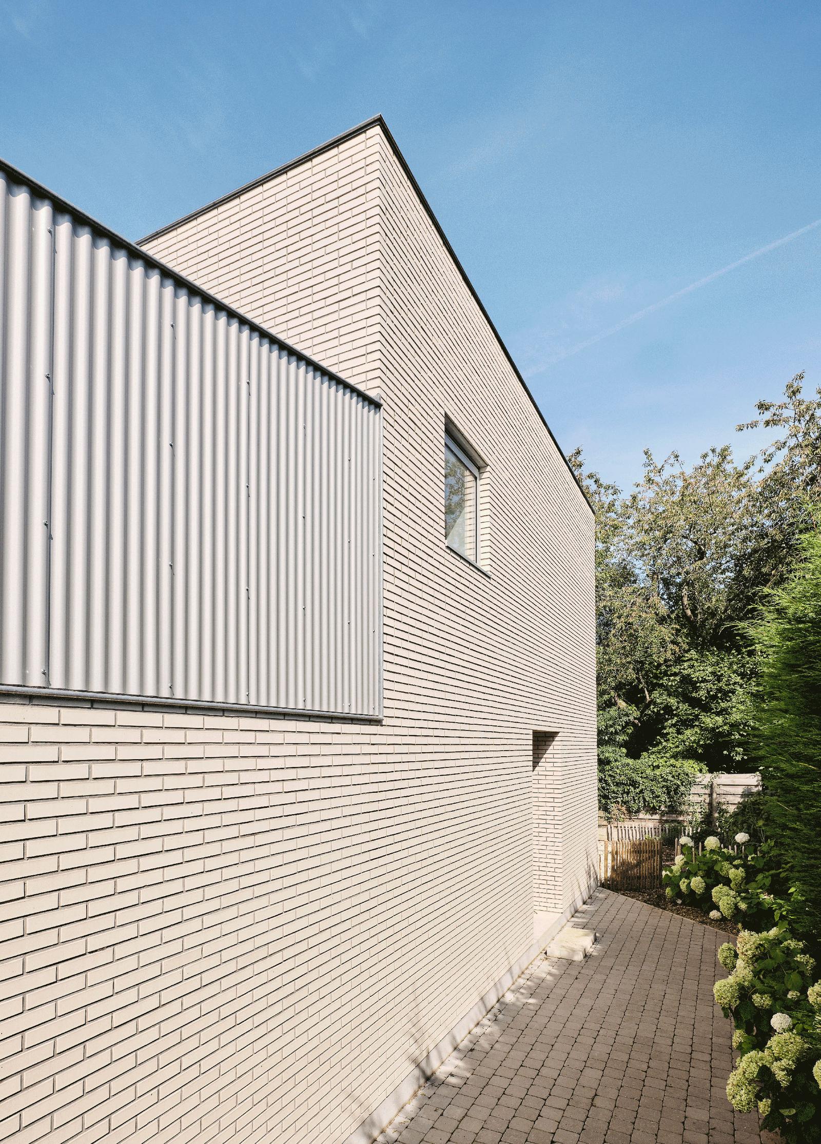 Gabled brick wall meeting a tall corrugated metal screen