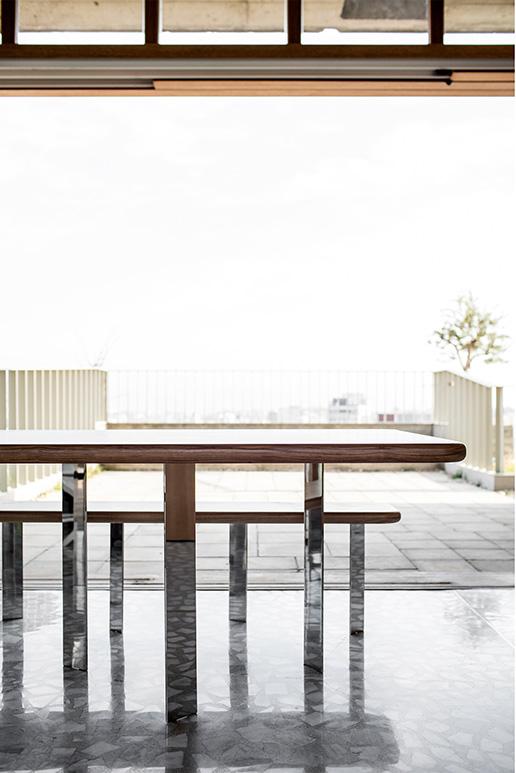 Low timber table overlooking a terrace and distant water