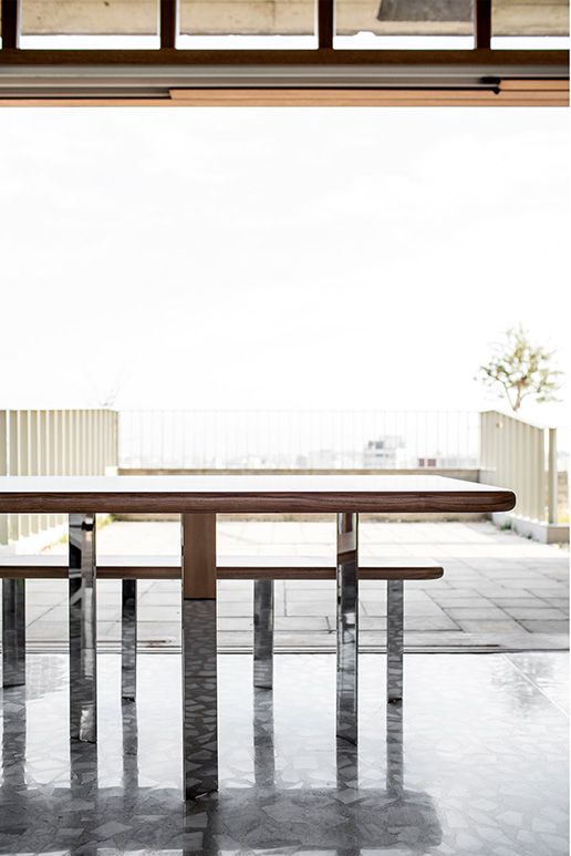 Low timber table overlooking a terrace and distant water