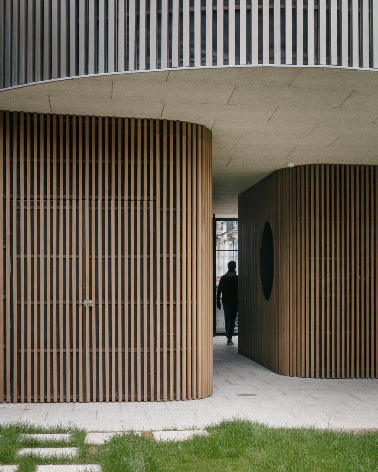 Covered passage with rounded timber walls at the Koto housing project