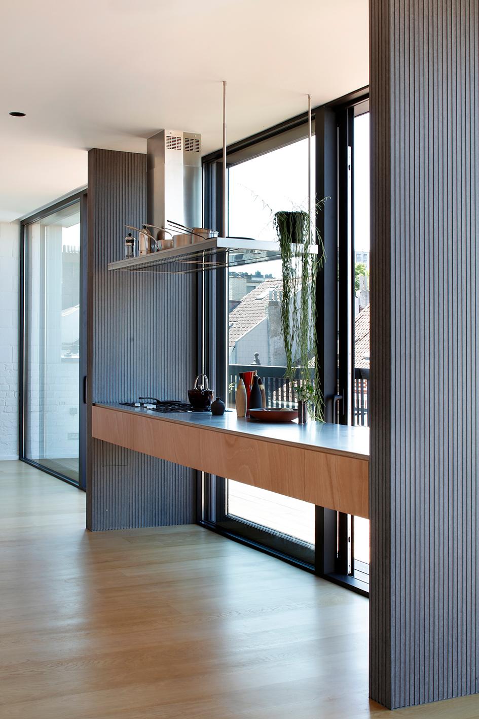 Timber kitchen counter running beside floor-to-ceiling glazing