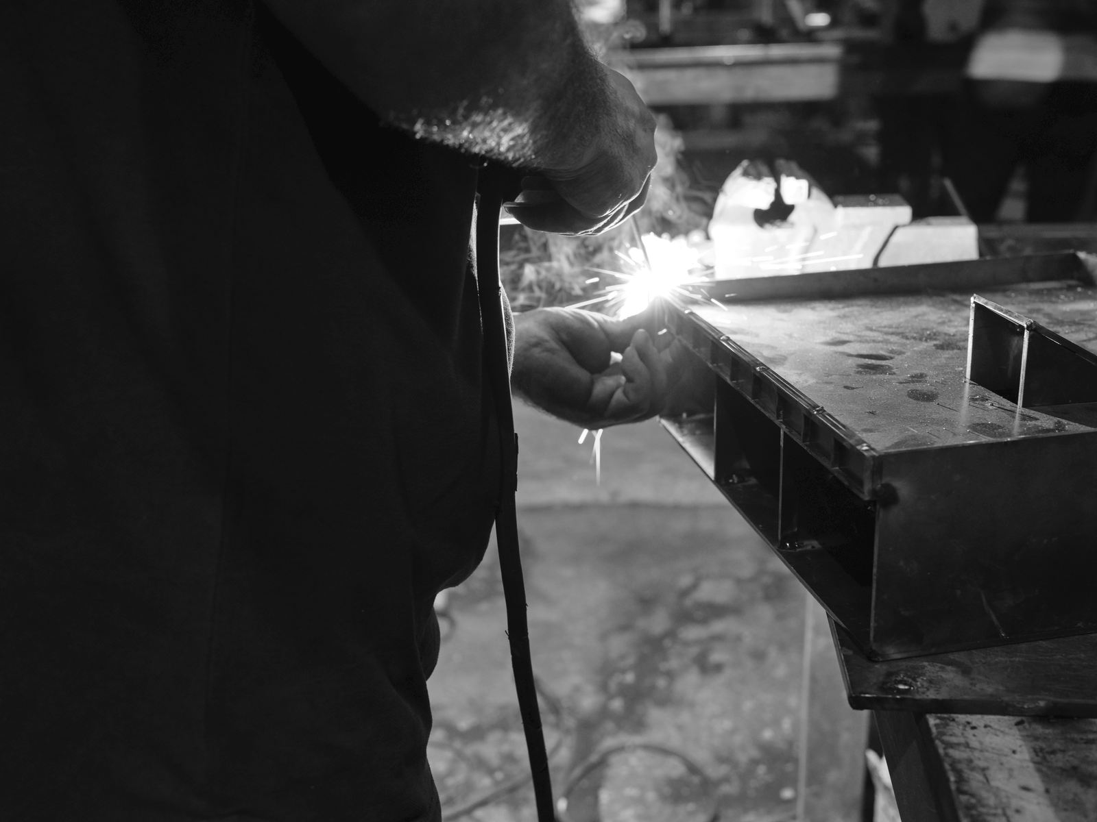 Metalworker welding the edge of a rectangular steel box