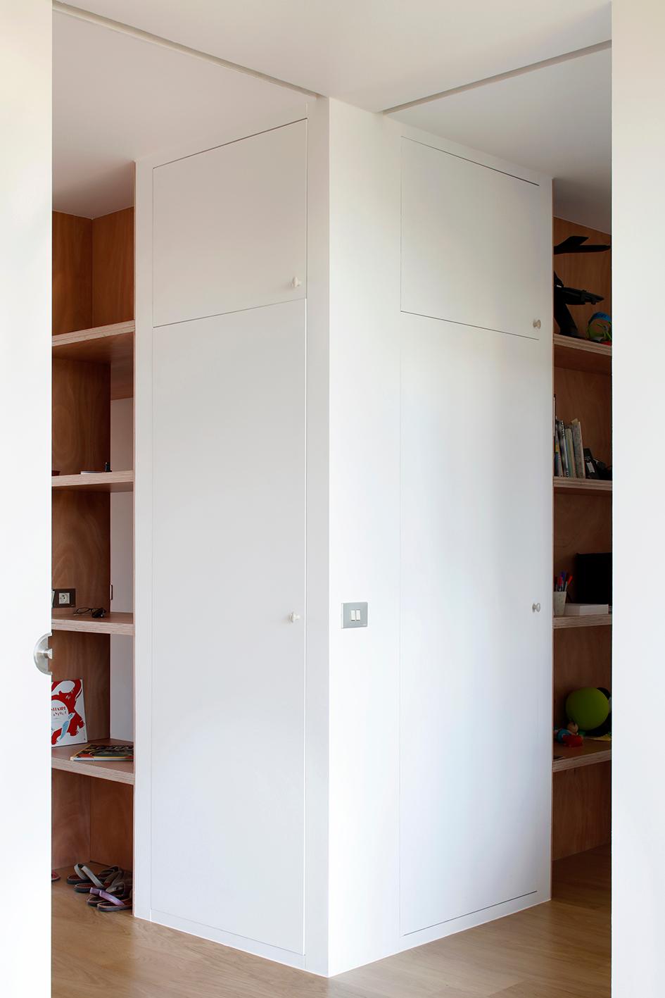 White cabinetry wrapping a timber-lined corner niche