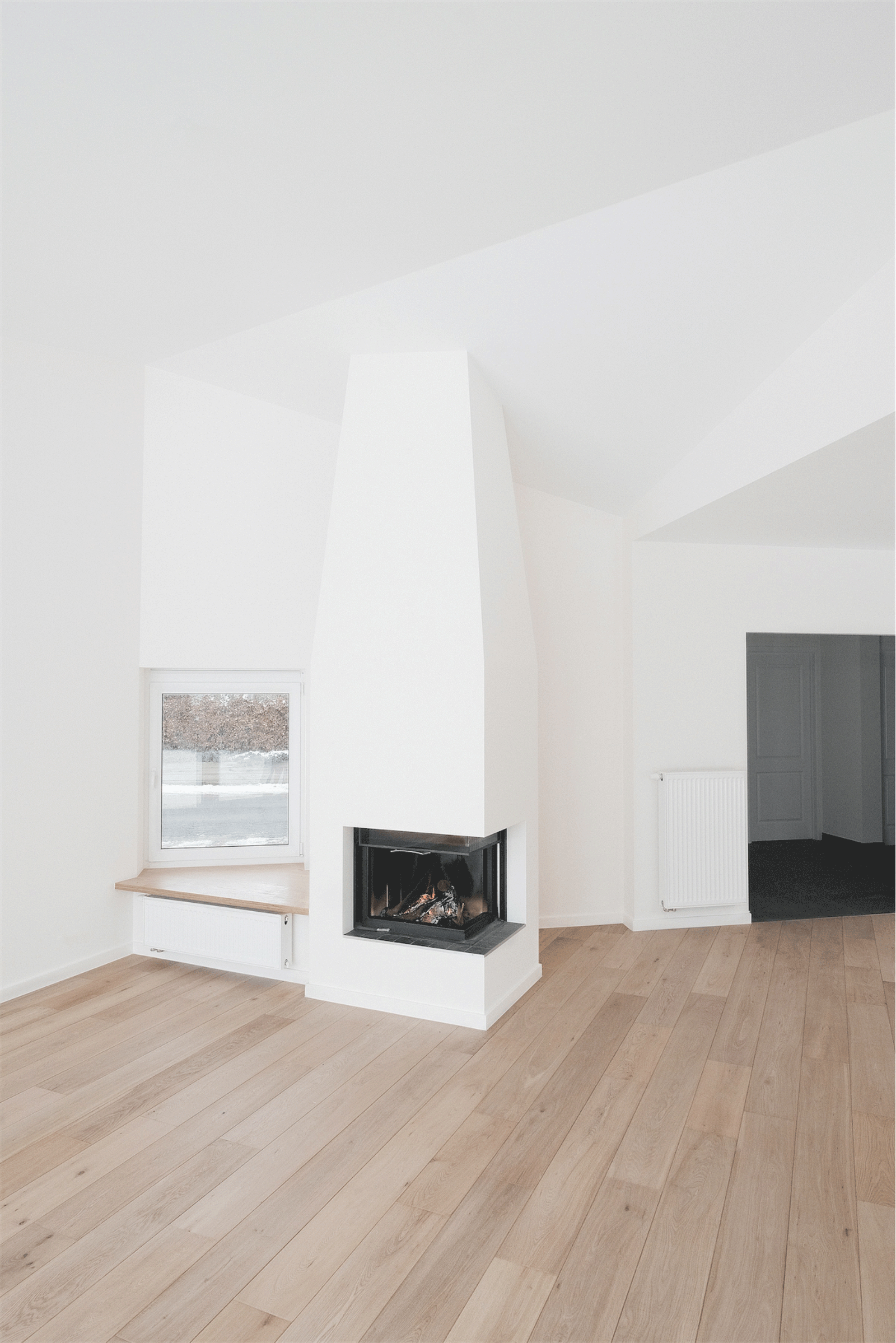 Corner fireplace between white walls and a low window