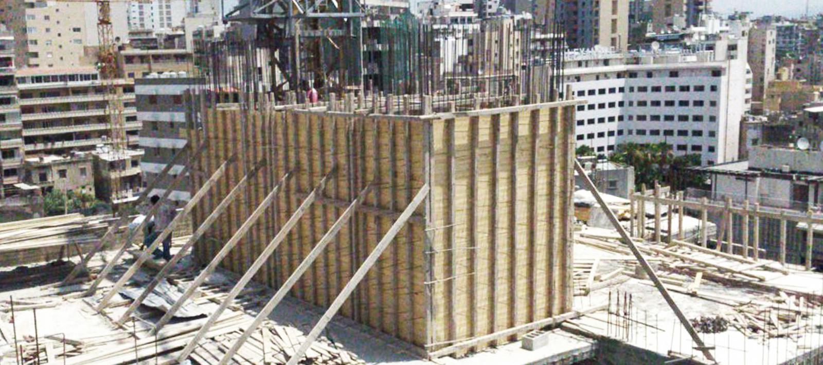 Construction view of tall timber formwork rising above the city