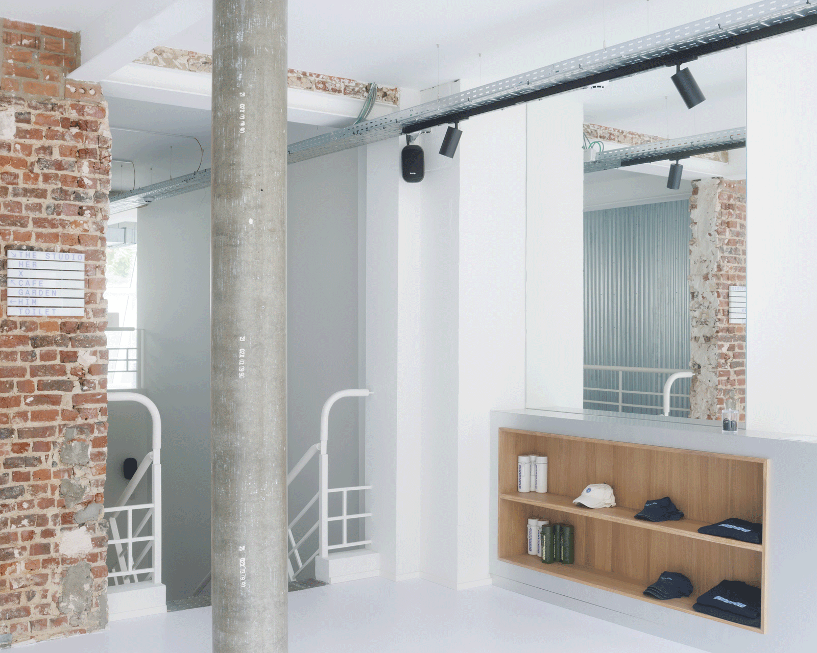 Timber display shelf beneath exposed brick and white structure