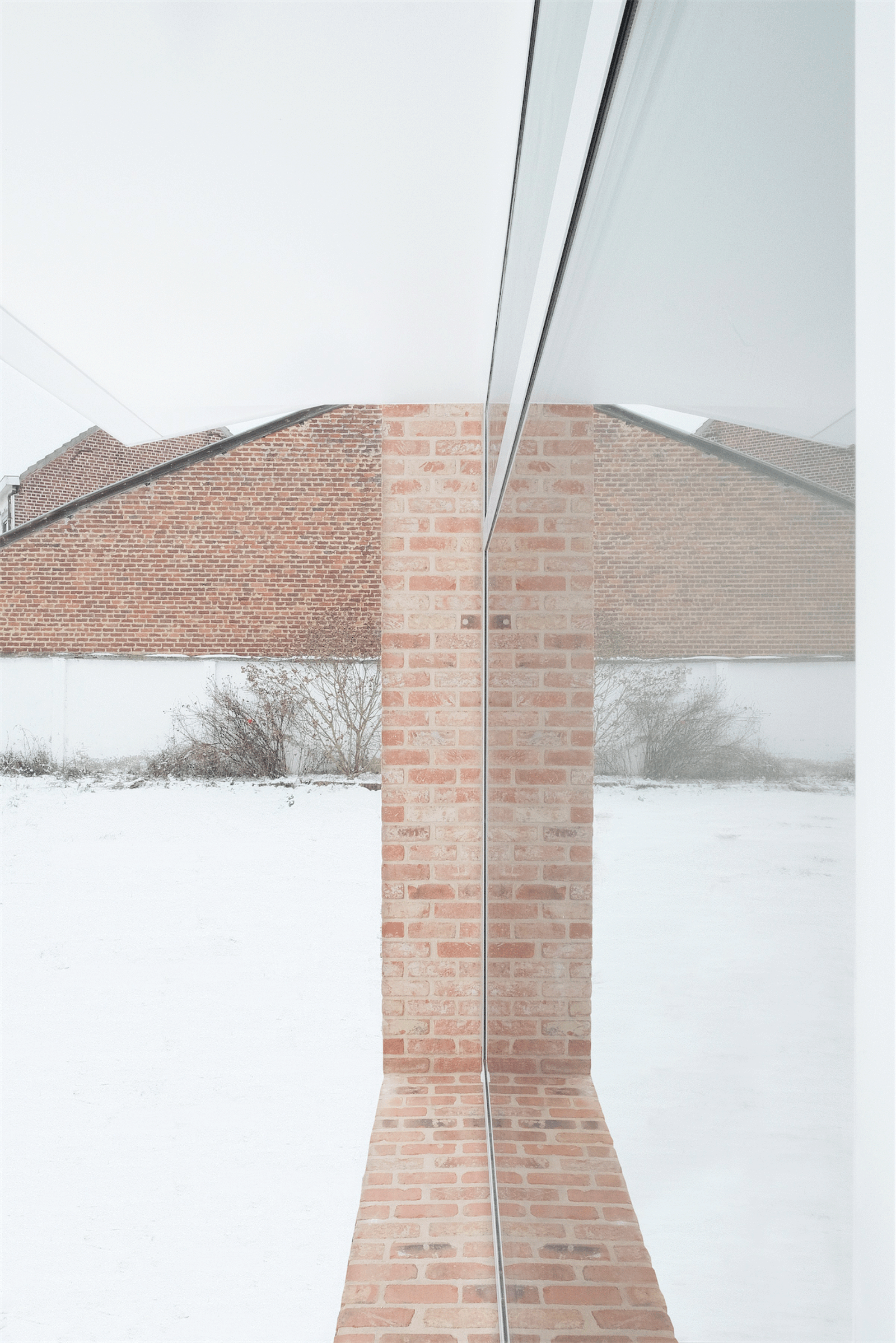 Thin brick wall dividing two snowy outdoor spaces