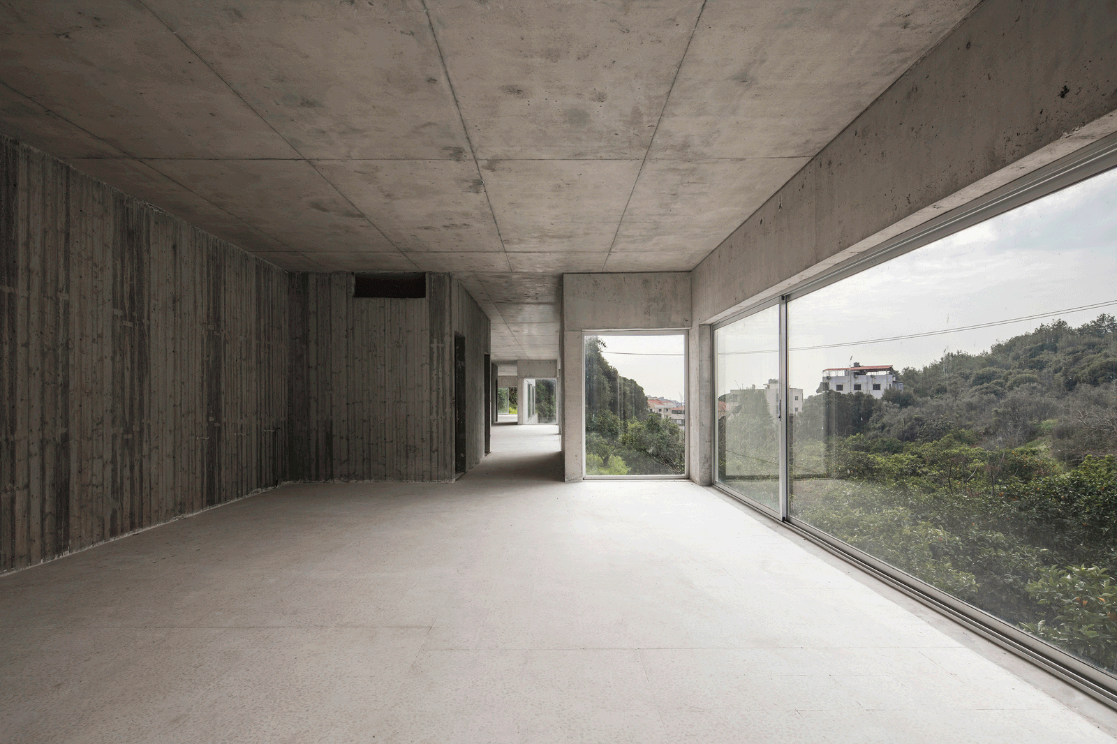 Long concrete room with full-height glazing toward the hillside