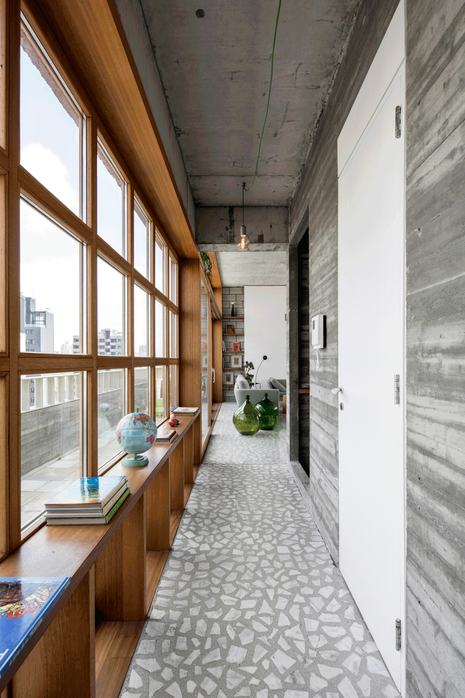 Long glazed corridor with a timber window ledge and terrazzo floor