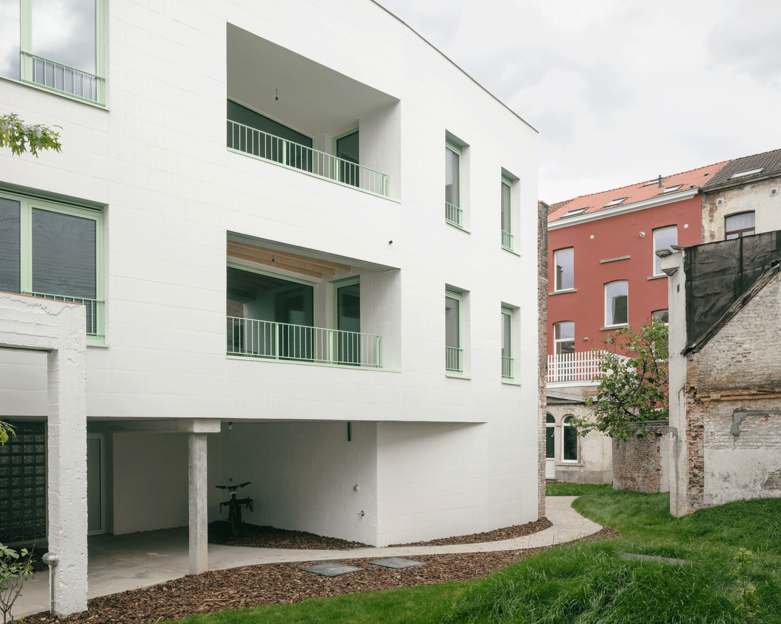White residential wing raised above a sheltered garden passage