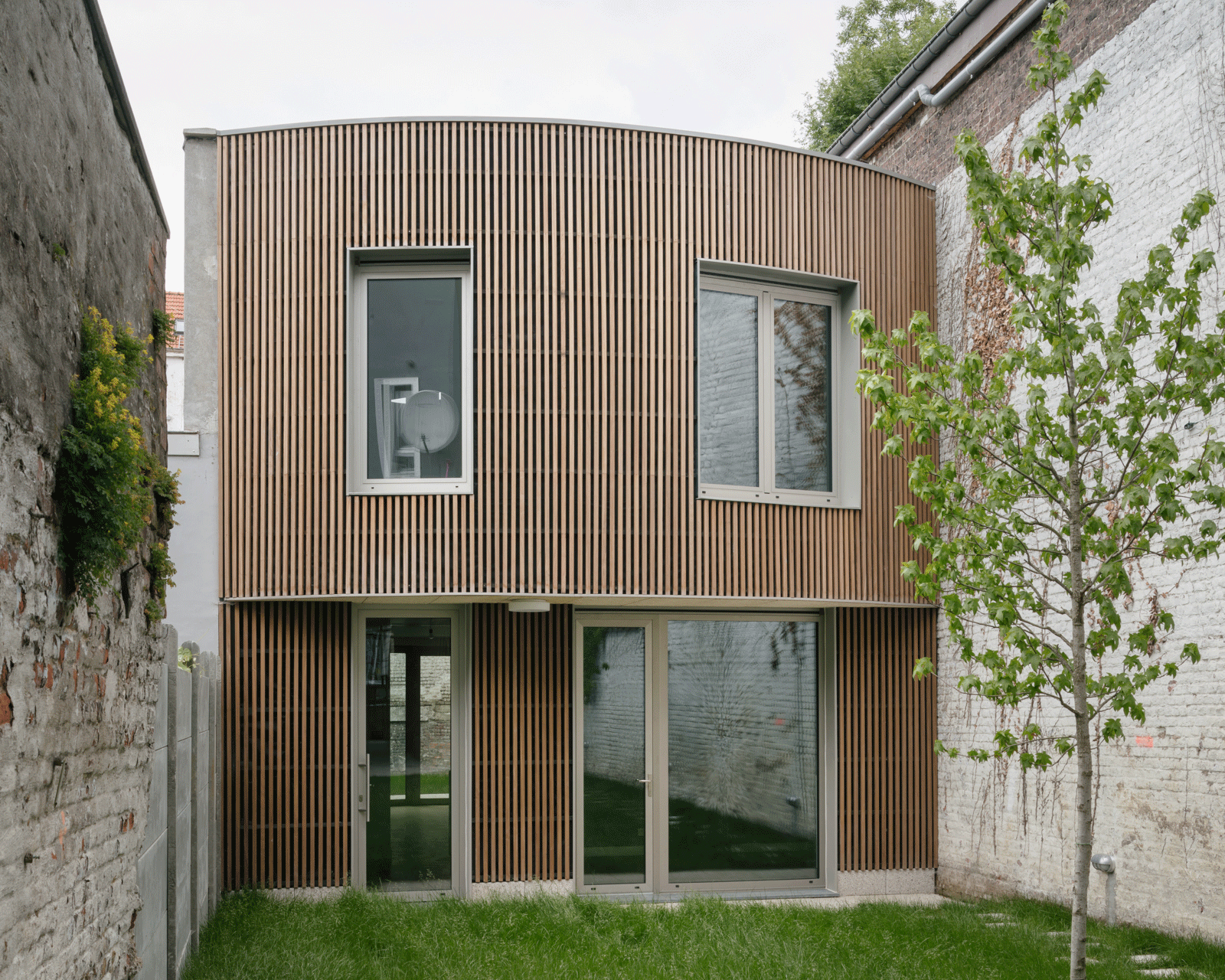 Rounded timber garden façade with large ground-floor doors