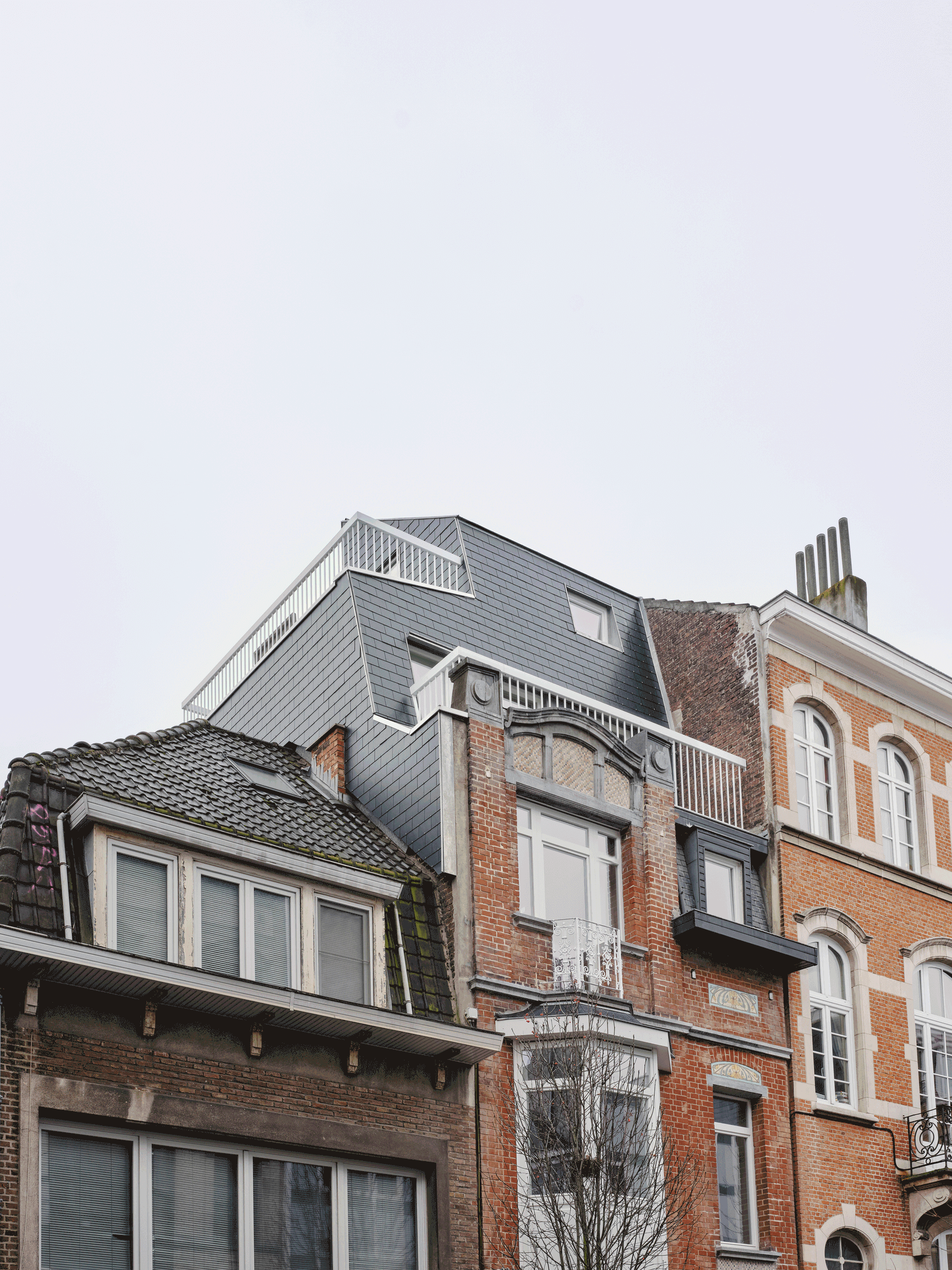 Street view of the dark rooftop addition above the brick house