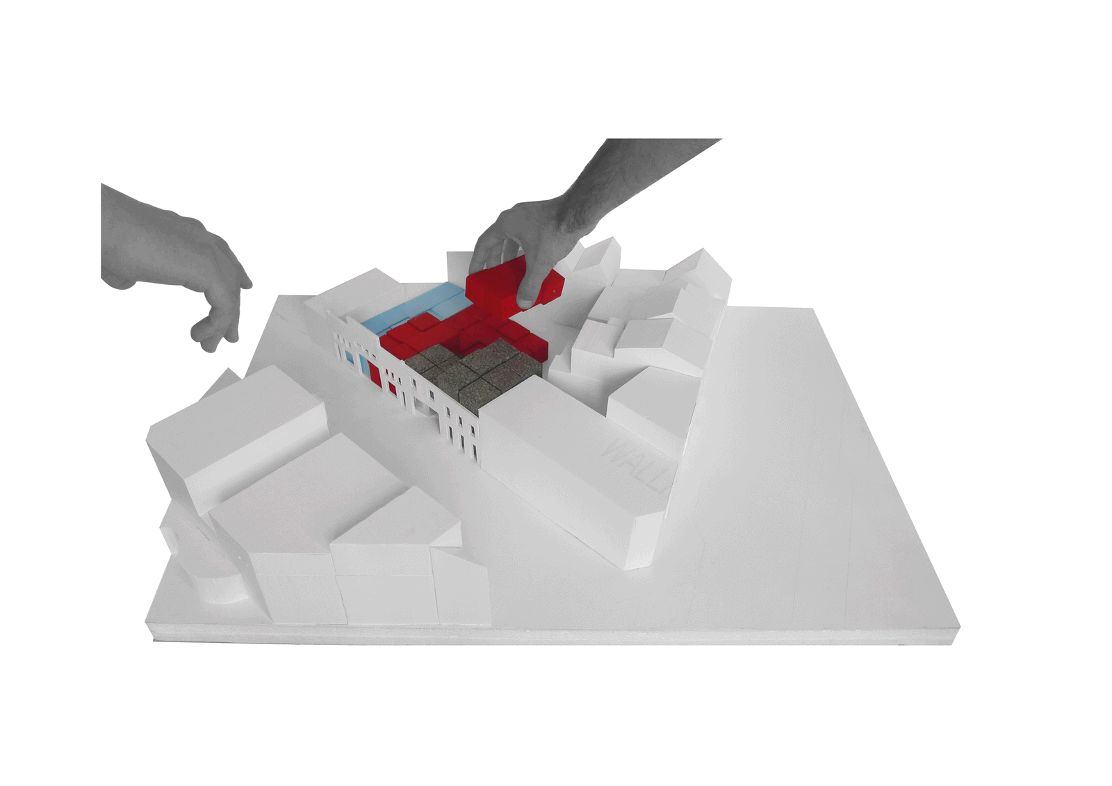 Hands arranging red programme blocks across the site model