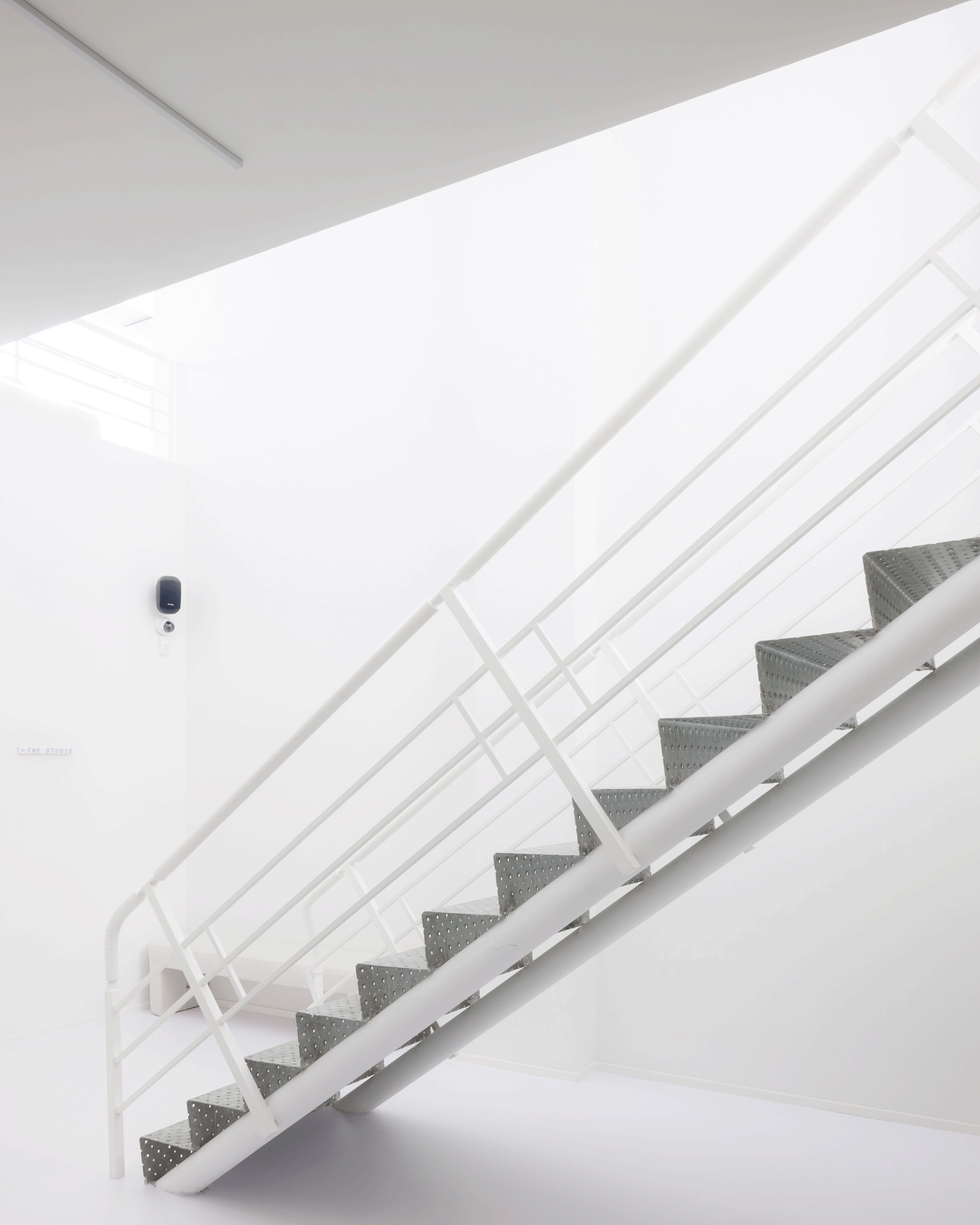 White metal stair rising through the roof-lit interior