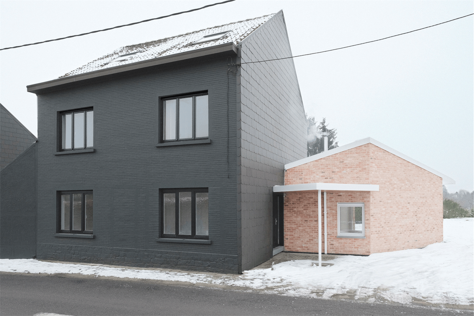Front view of the dark gabled house and brick entrance wing