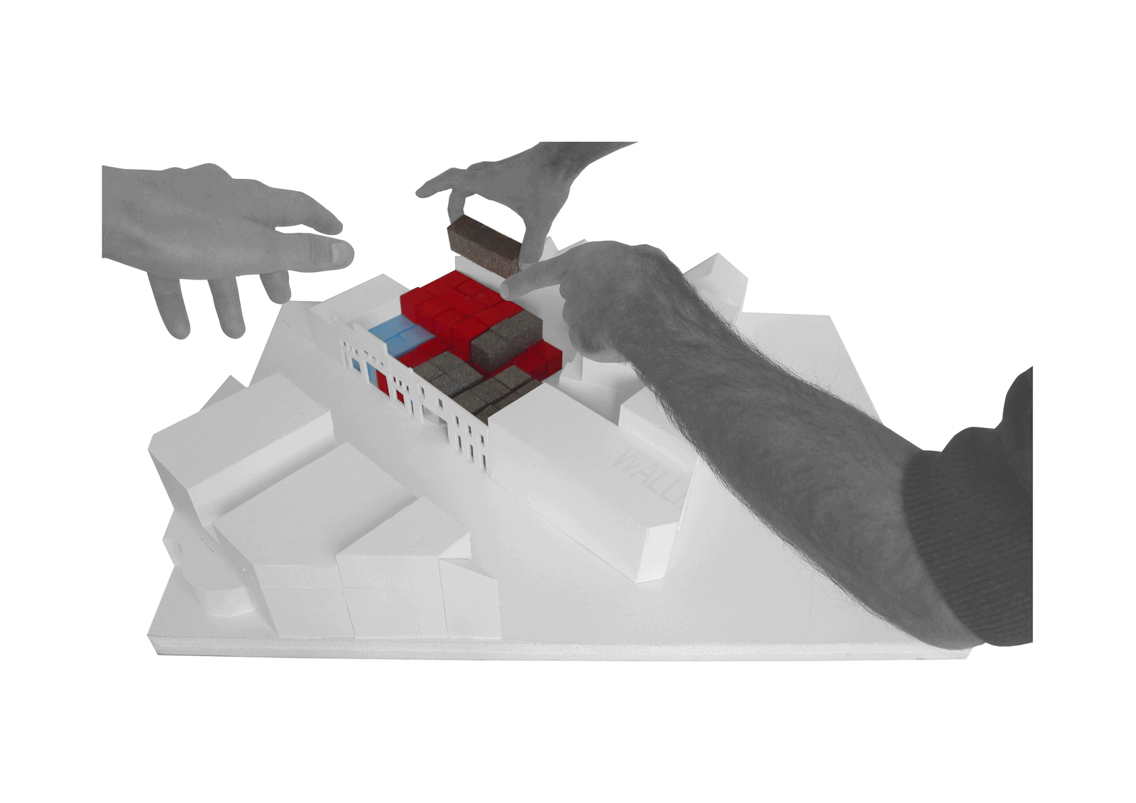 Hands positioning red programme blocks in a site model