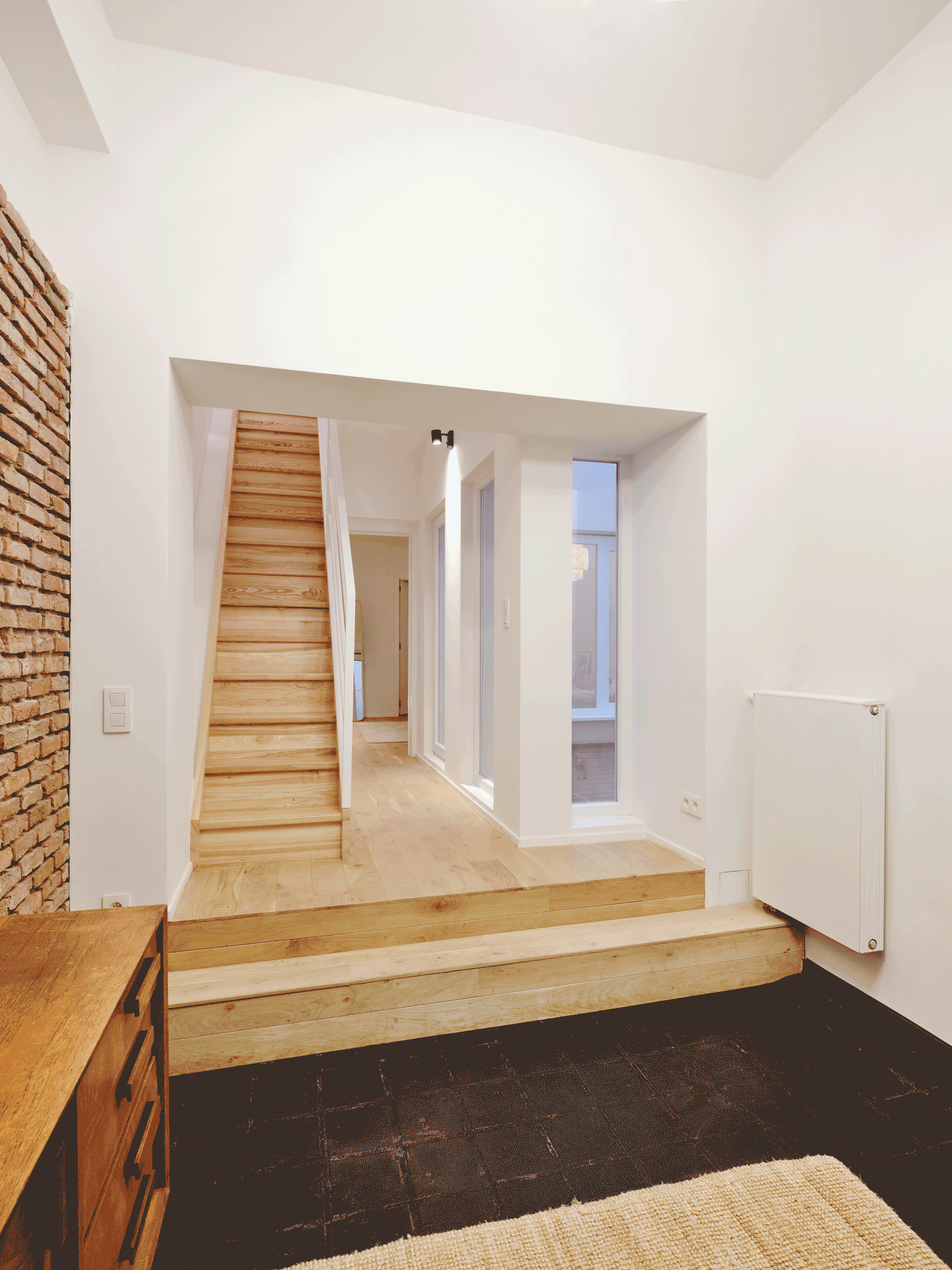 Short timber stair connecting two white interior levels