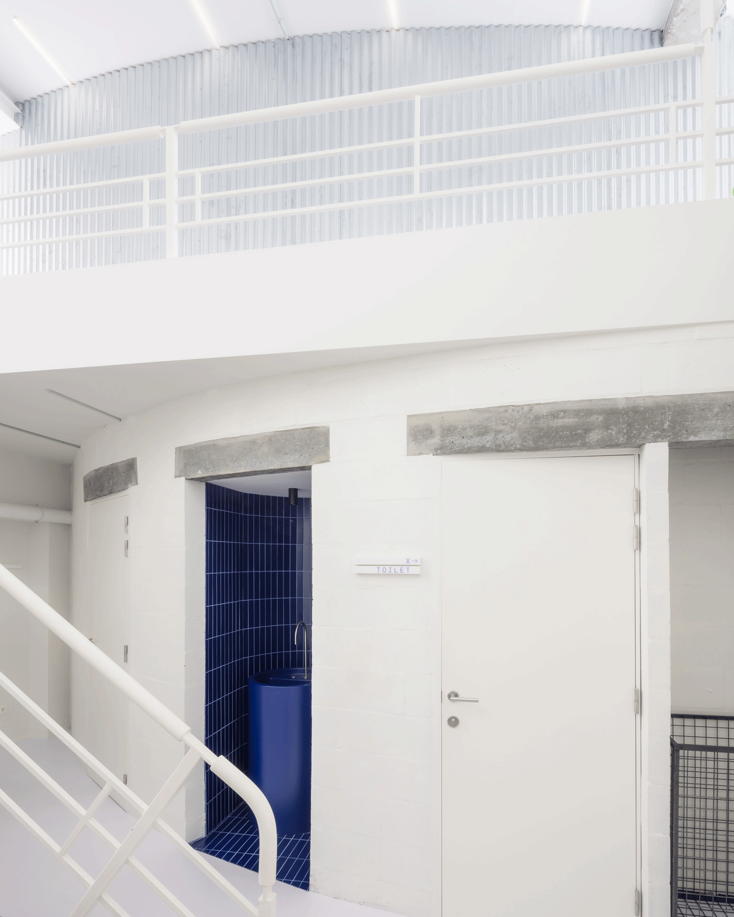 White mezzanine and stair above a deep blue doorway