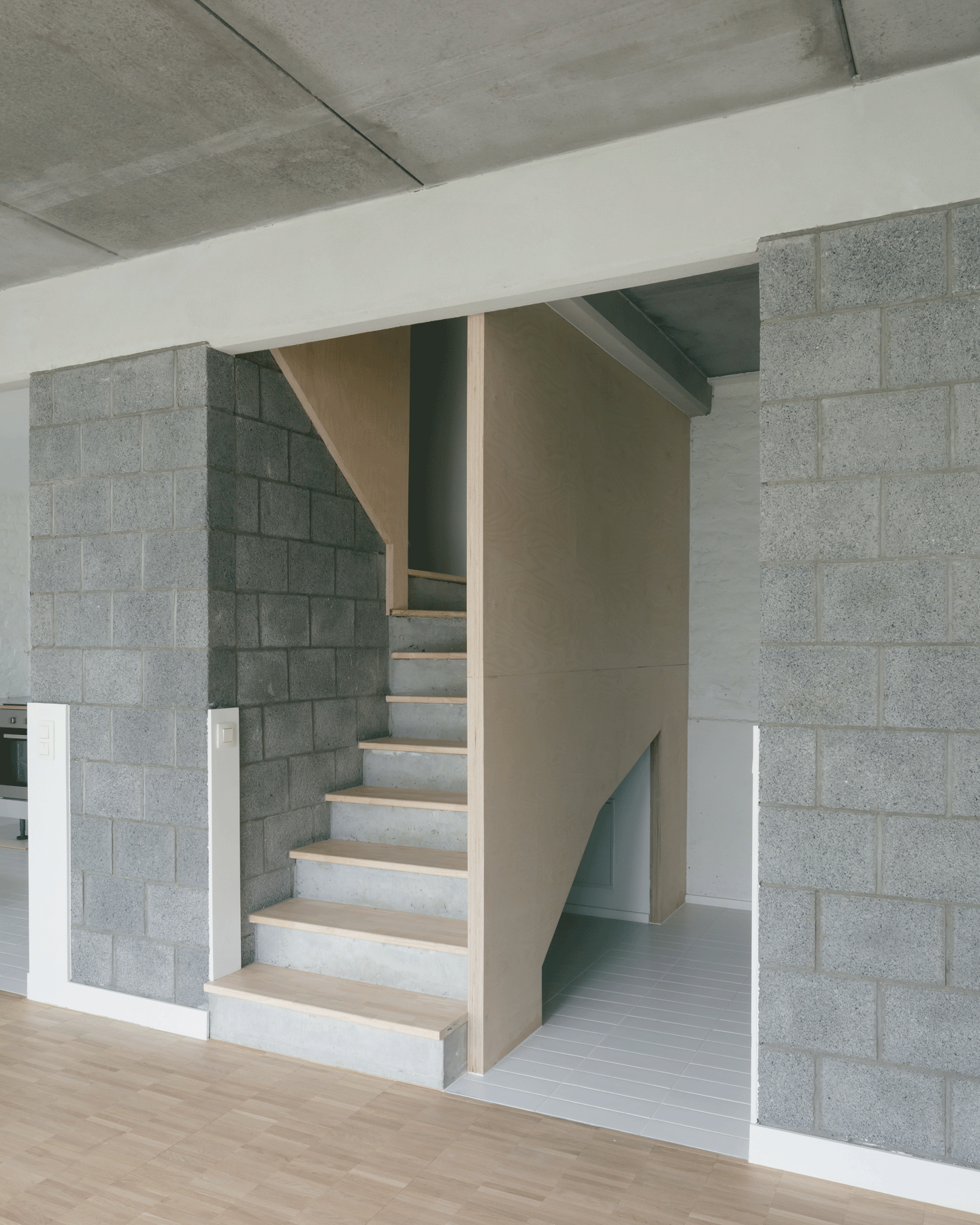 Unfinished masonry stair rising between concrete block walls