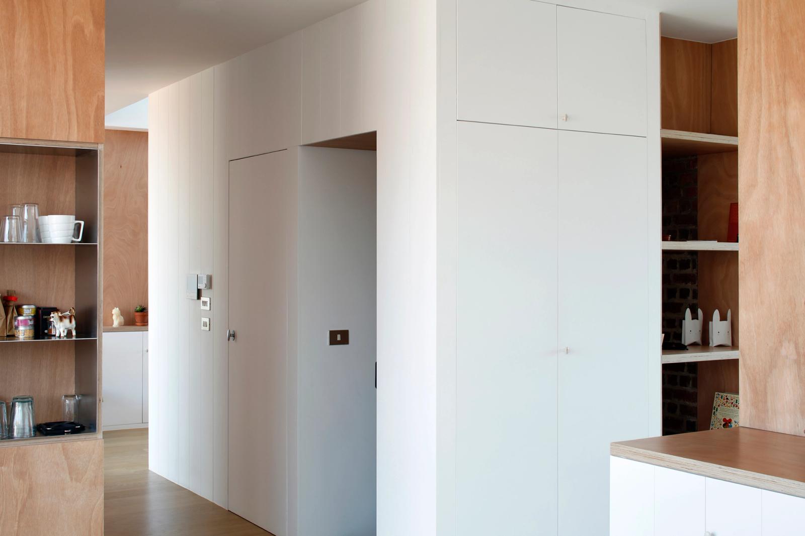 White and timber storage cabinets shaping the apartment entrance