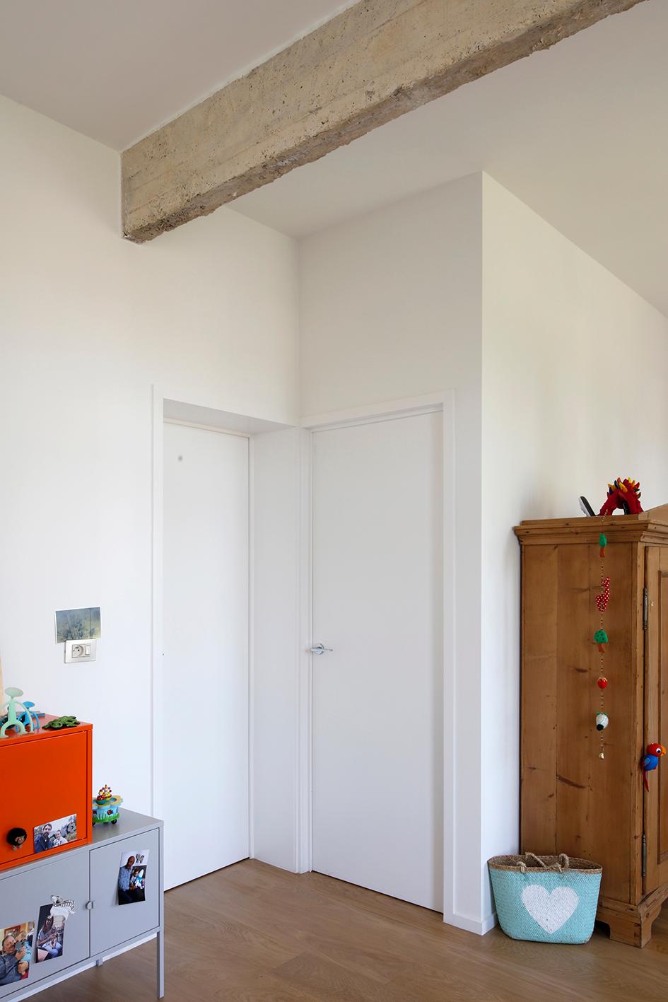 Entrance hall retaining a concrete beam above white doors