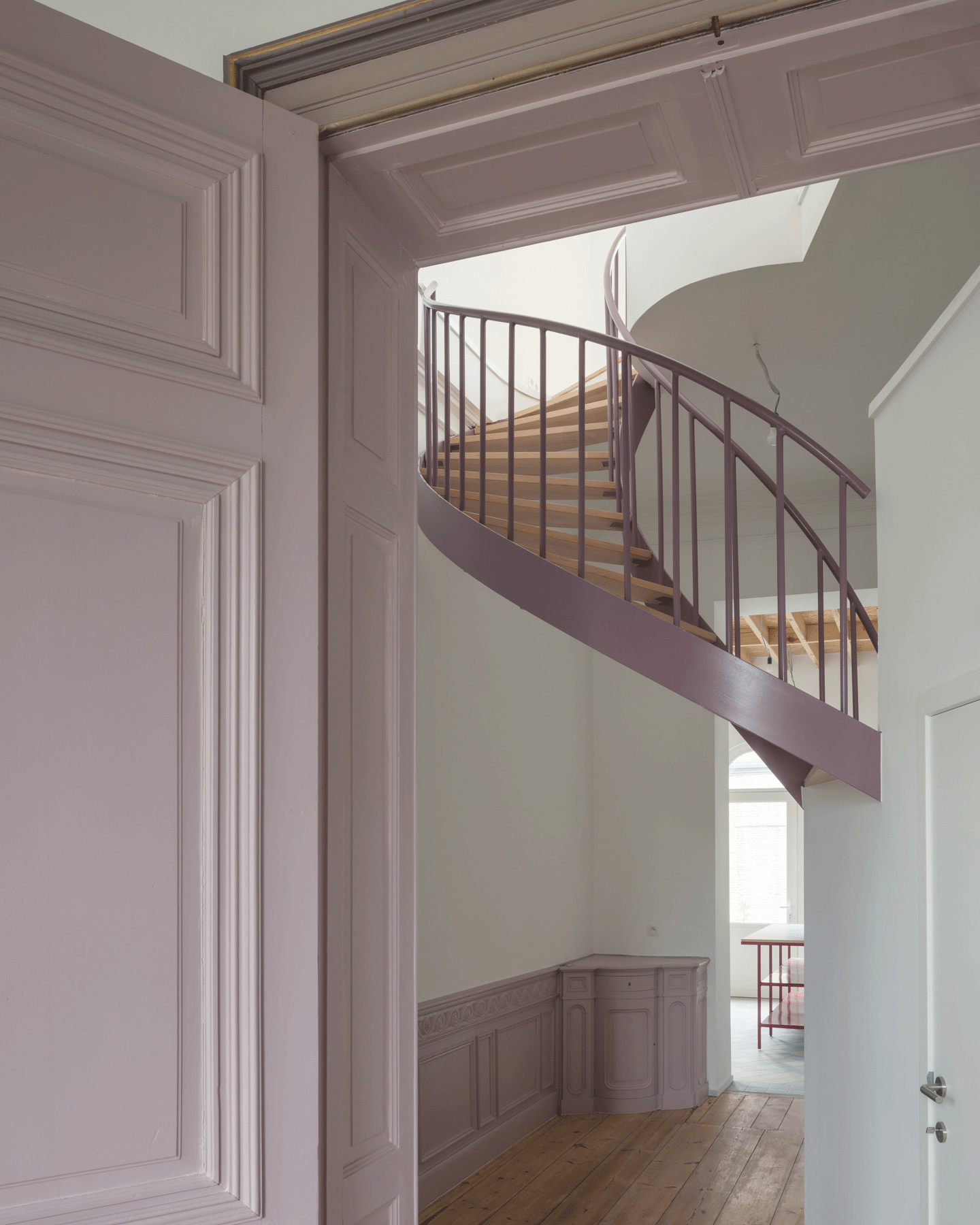 Historic doorway framing a red spiral stair in the next room
