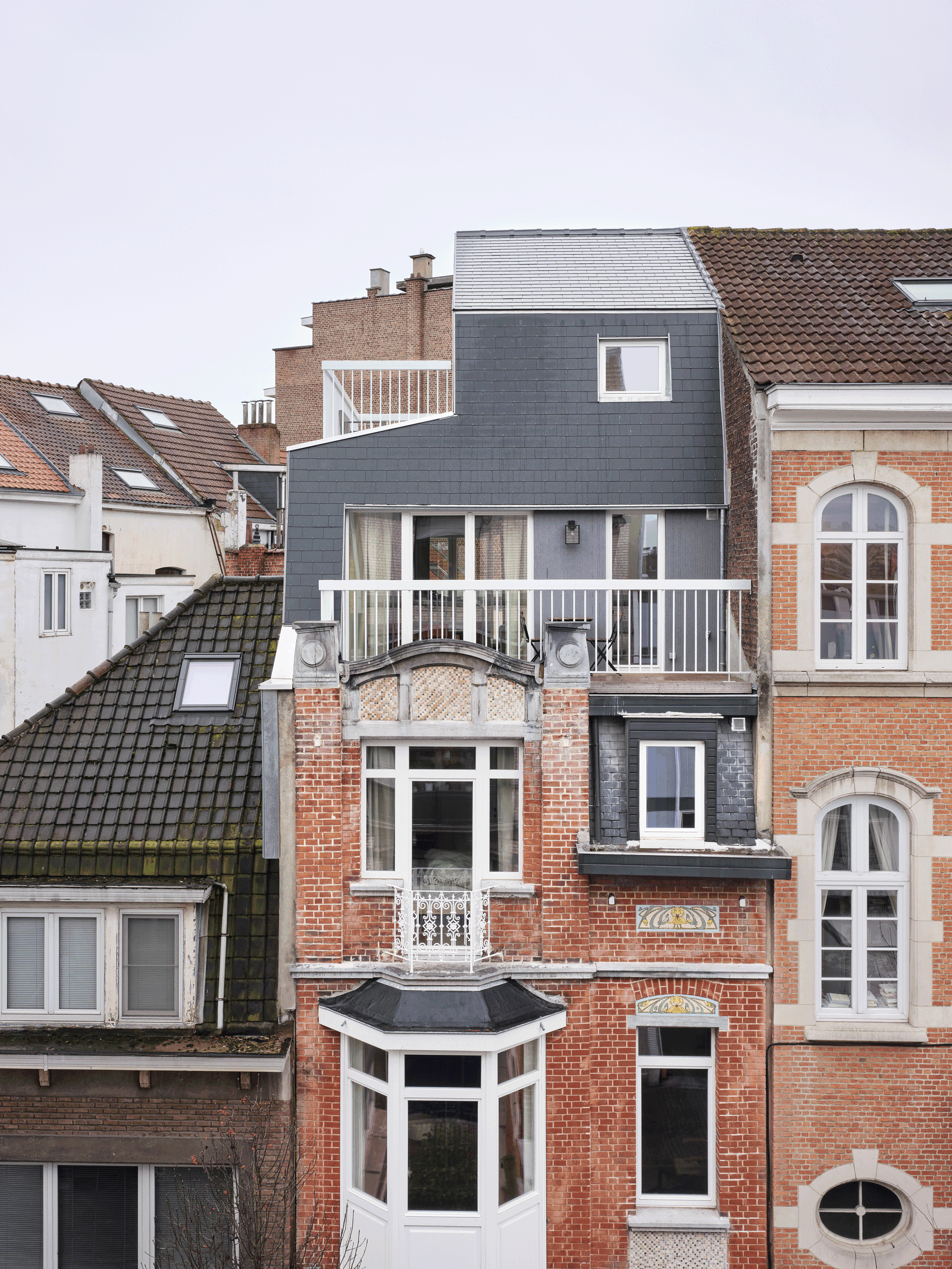 Front view of the house with its dark faceted roof addition